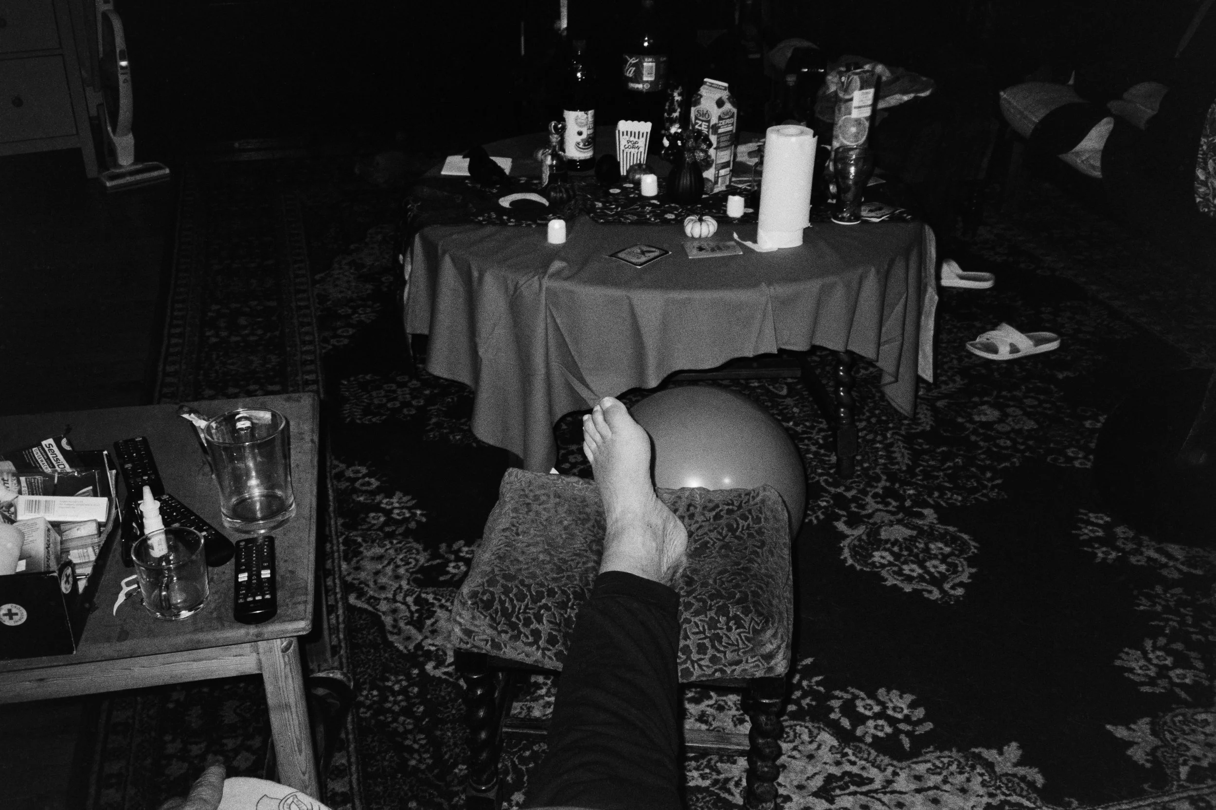 My father rests his swollen foot on a chair. 2025.