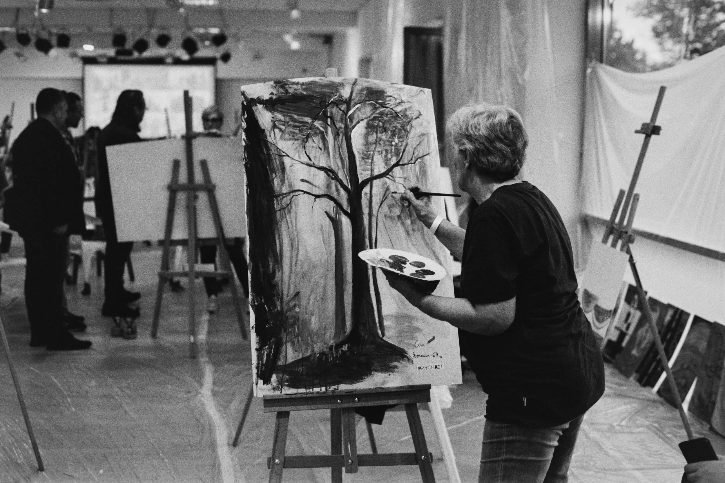 A woman paints a picture at a national art event for psychiatric patients. 2025.