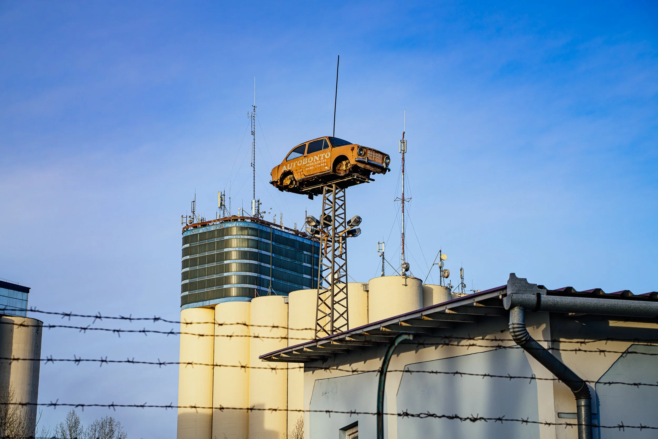 Car scrapyard, with grain silo in the background. 2025.