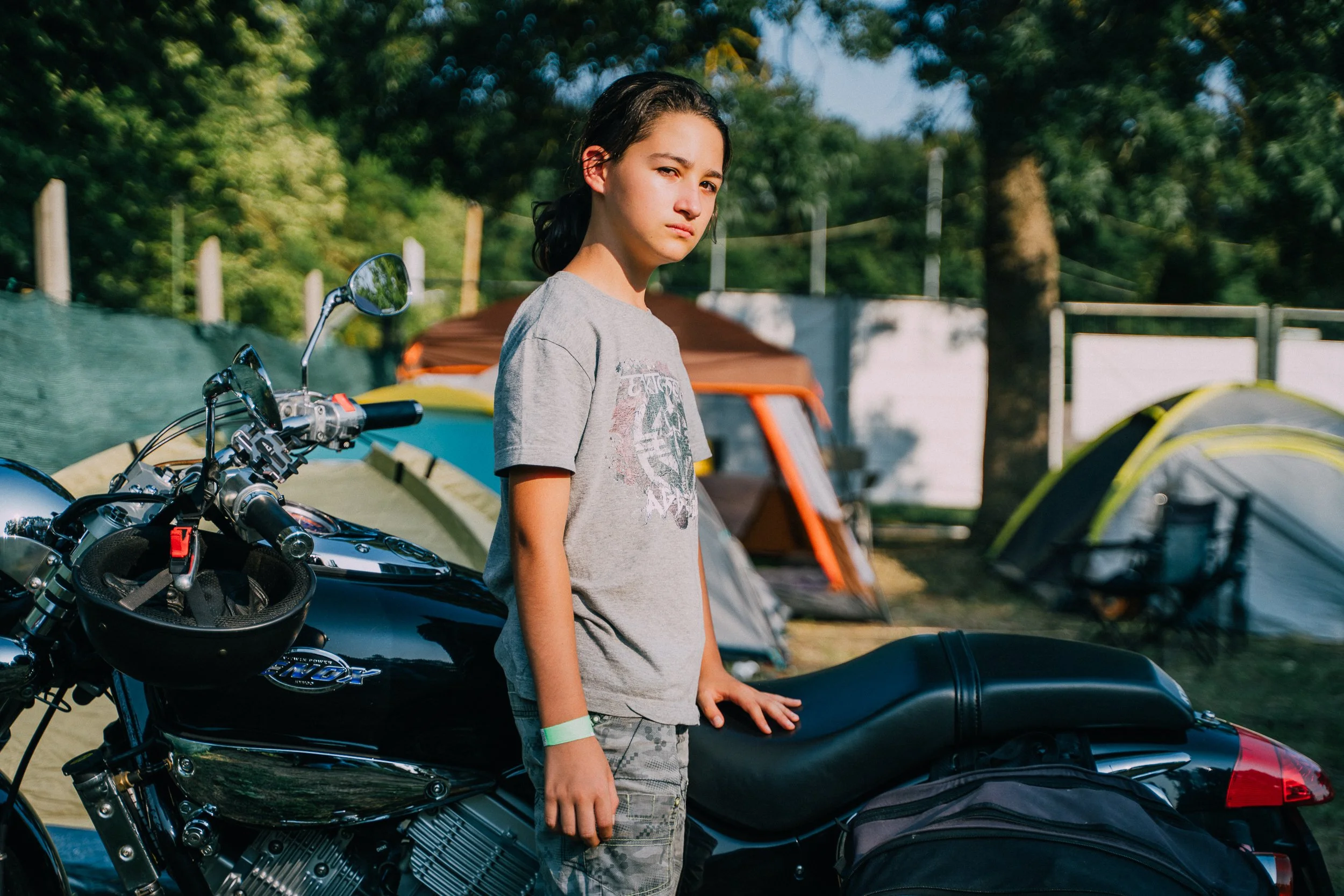 A boy stands next to his father's chopper. 2025.