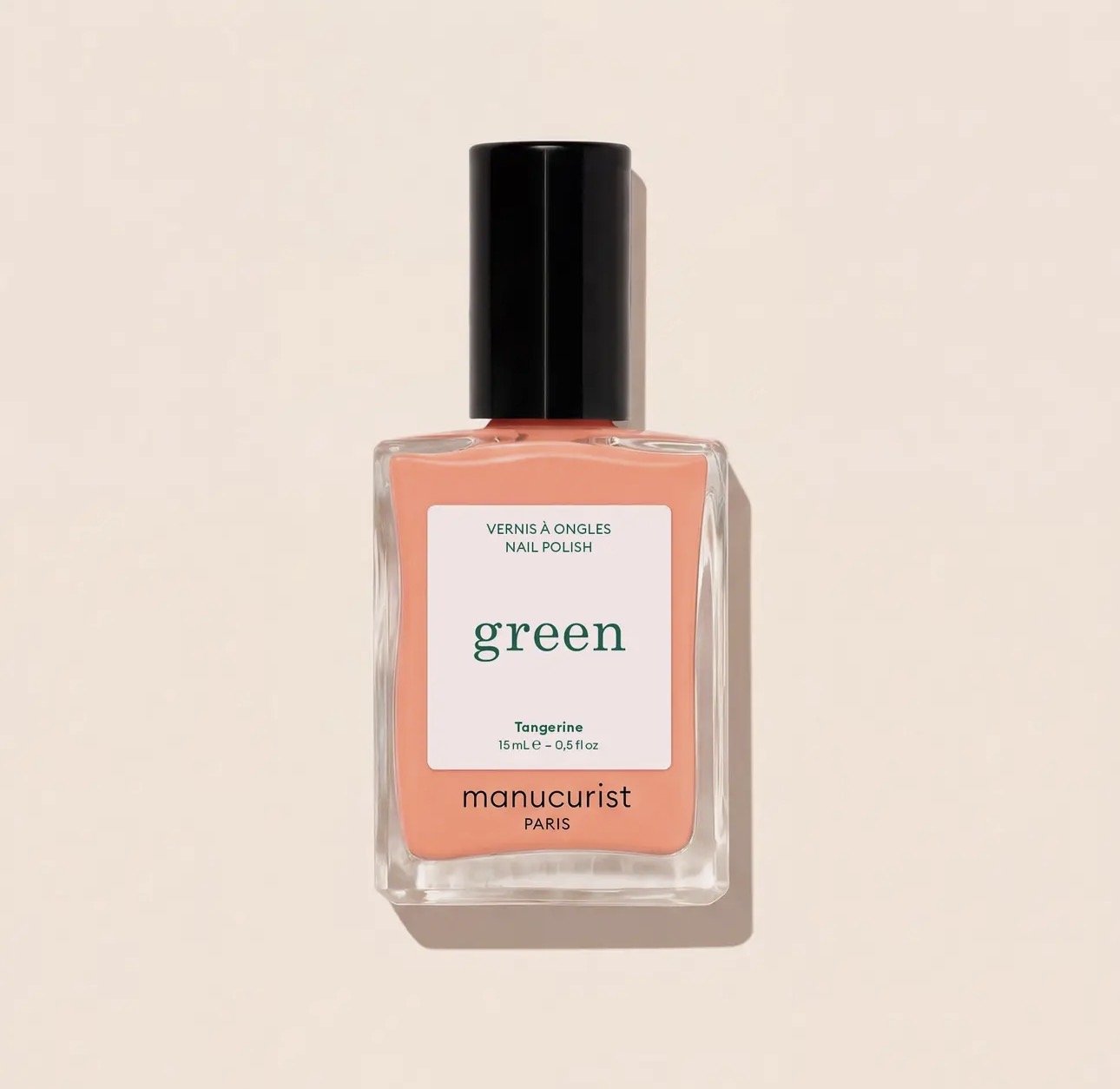 A bottle of Manucurist green nail polish in Tangerine color with a black cap and a white label on the front, placed against a light background.