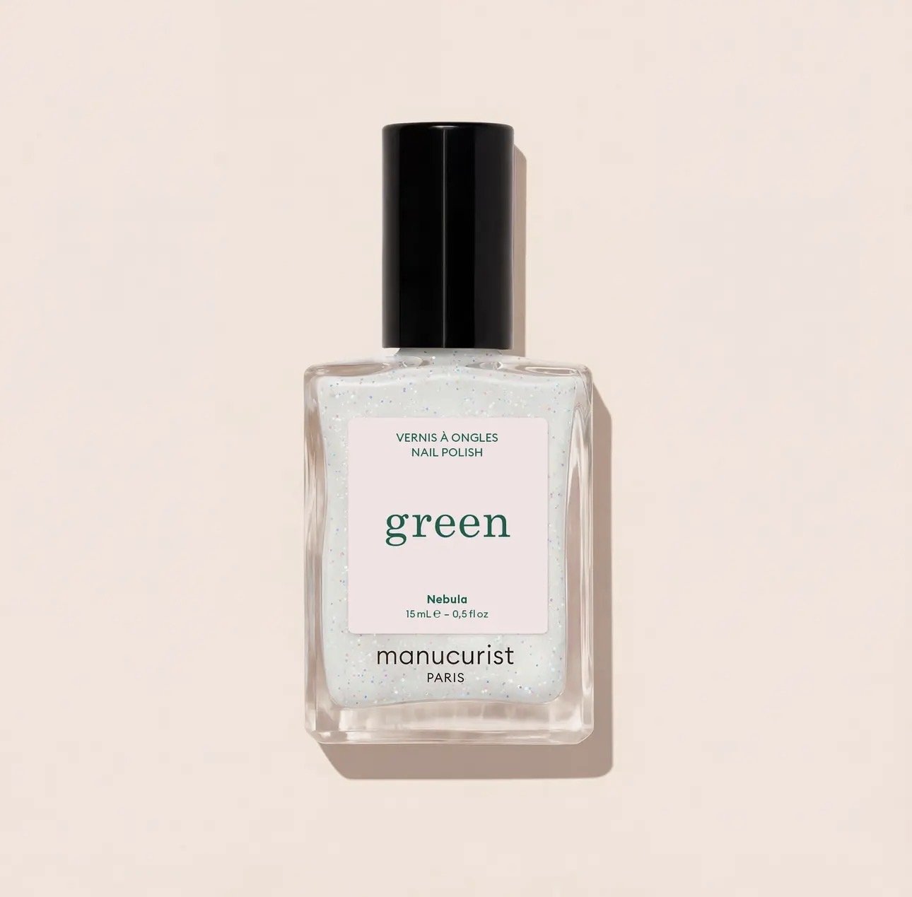 A clear glass bottle of Manicurist green-colored nail polish with a black cap, featuring a white label with green text that reads "green Nebula" and the brand "manucurist PARIS."