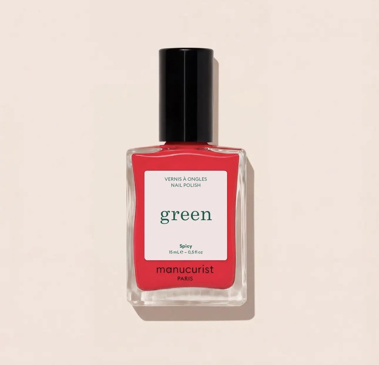 A bottle of Manicurist red nail polish with a black cap, labeled 'green Spicy Manucurist Paris.'
