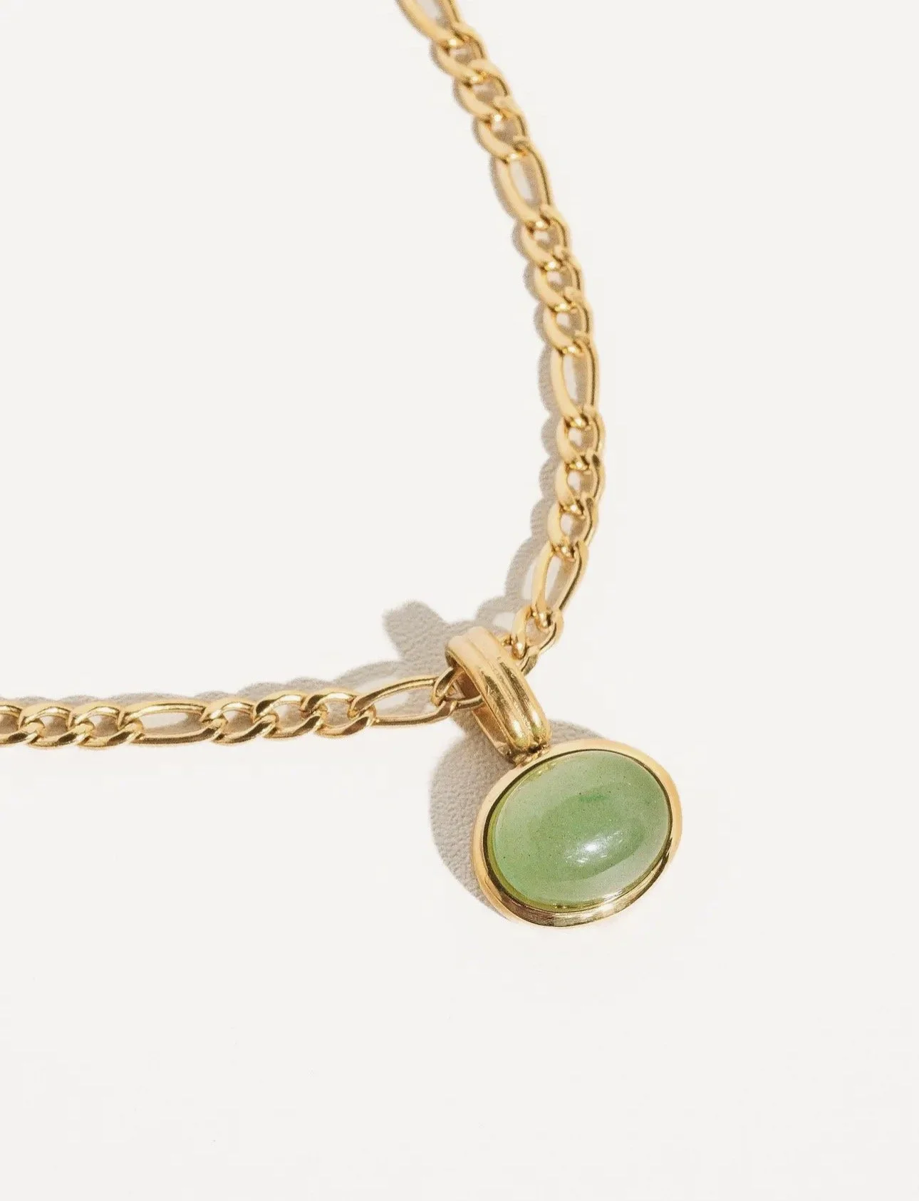 Gold chain necklace with a green circular pendant