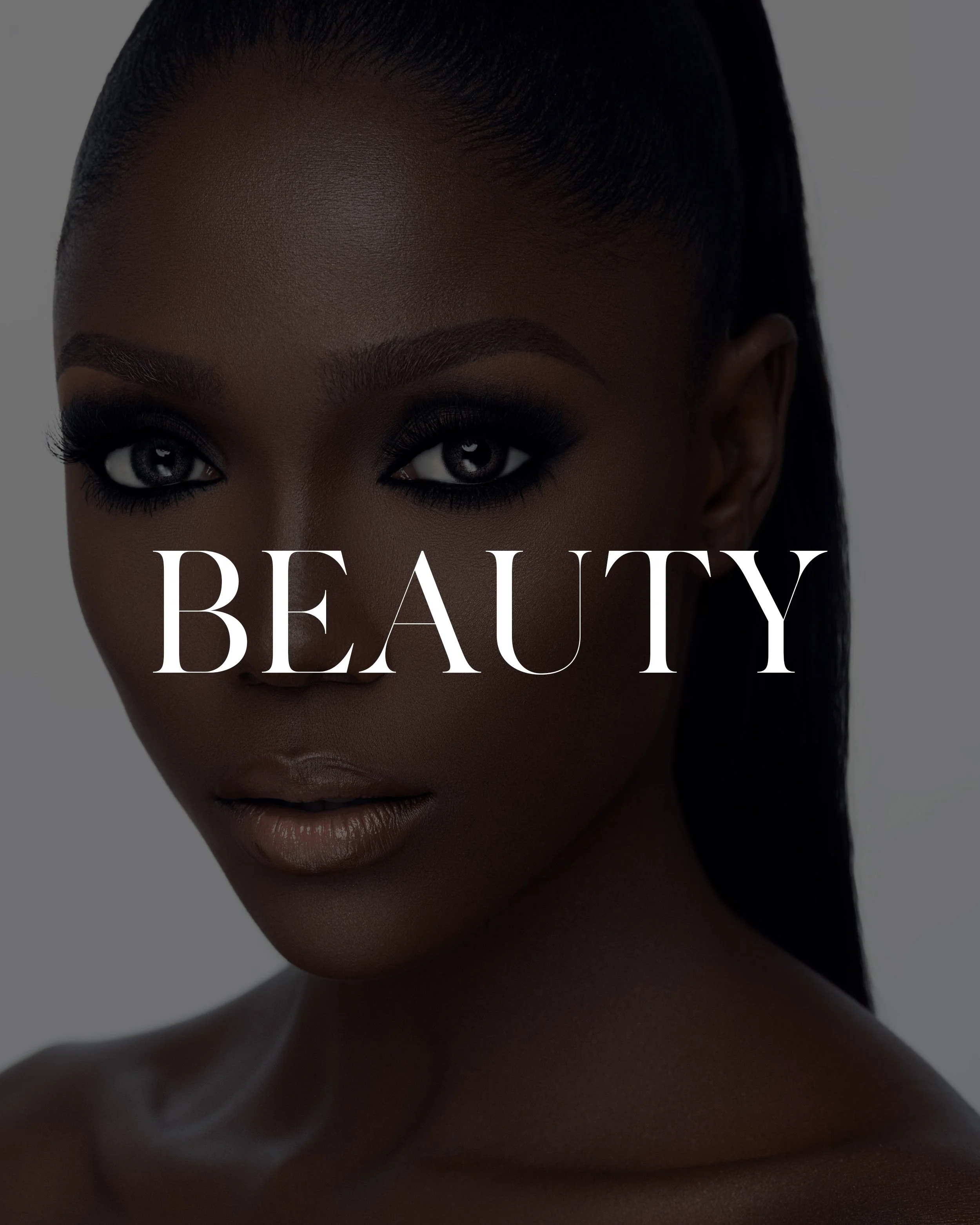 Close-up of a woman with dark skin, striking eyeliner, and shiny lips, with the word 'BEAUTY' overlaid in white text.