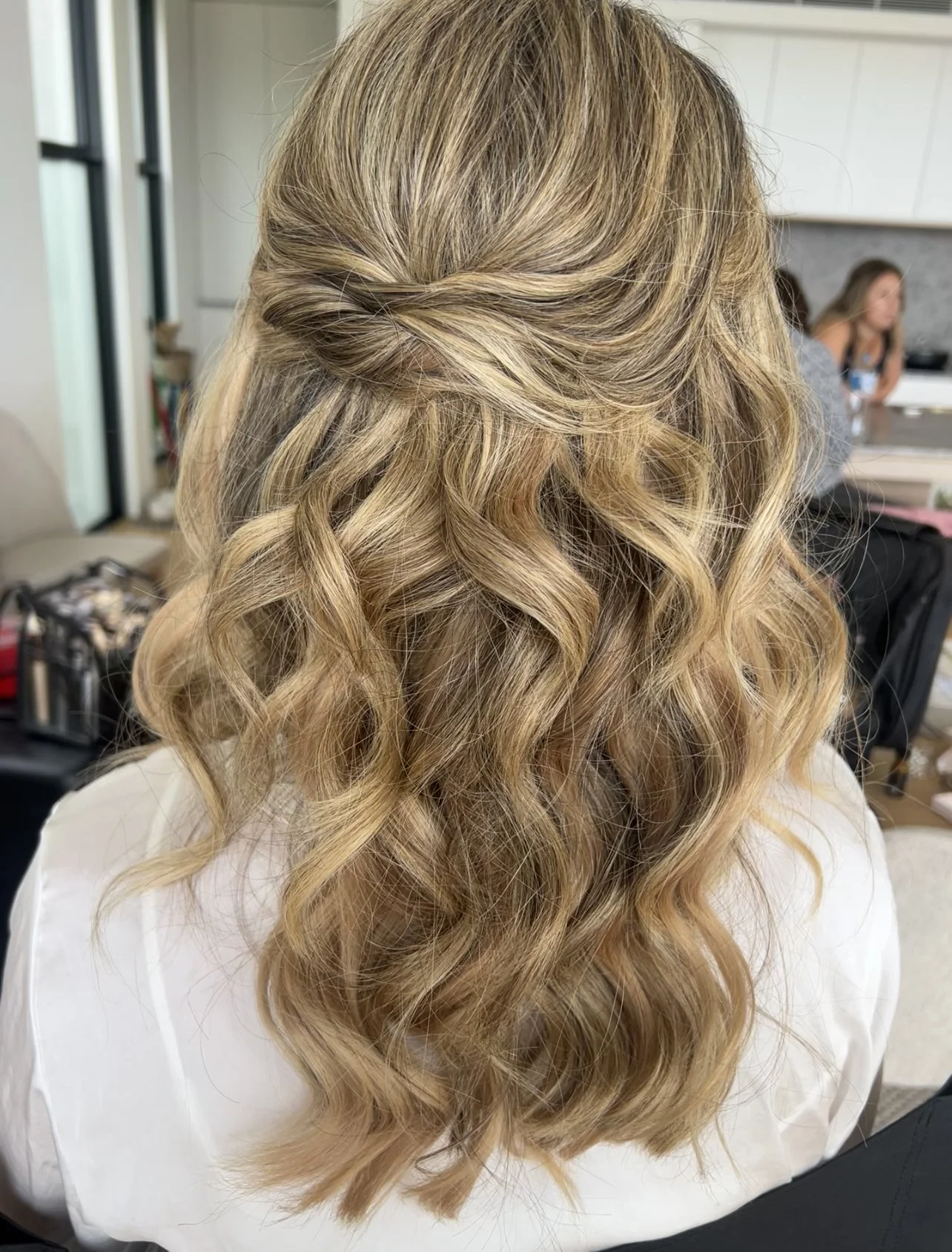 Back of a woman's head with styled blonde curly hair in a salon.