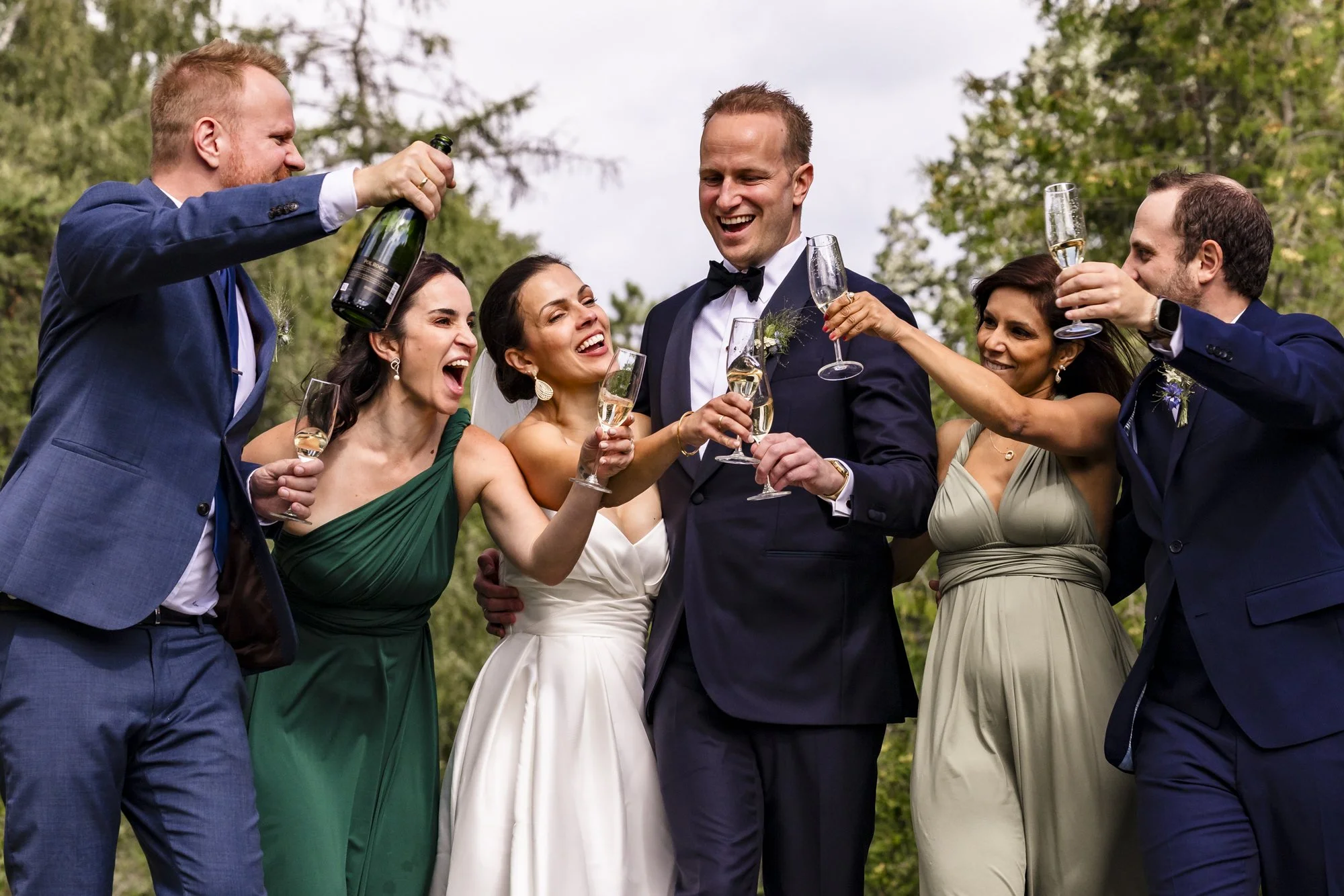 Gruppemennesker i formelle klær som feirer med champagne utendørs.