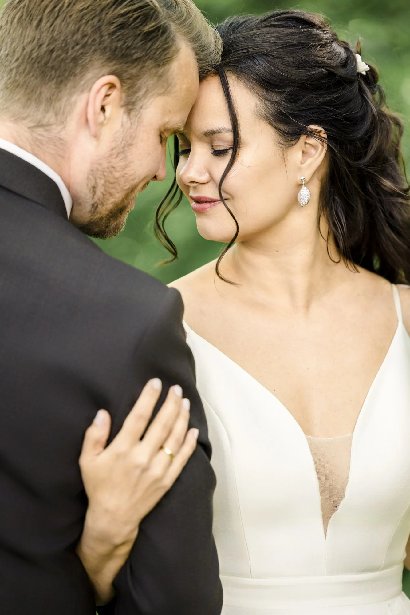 Et romantisk øyeblikk mellom et brudepar med pannen mot pannen, begge smilende forsiktig.