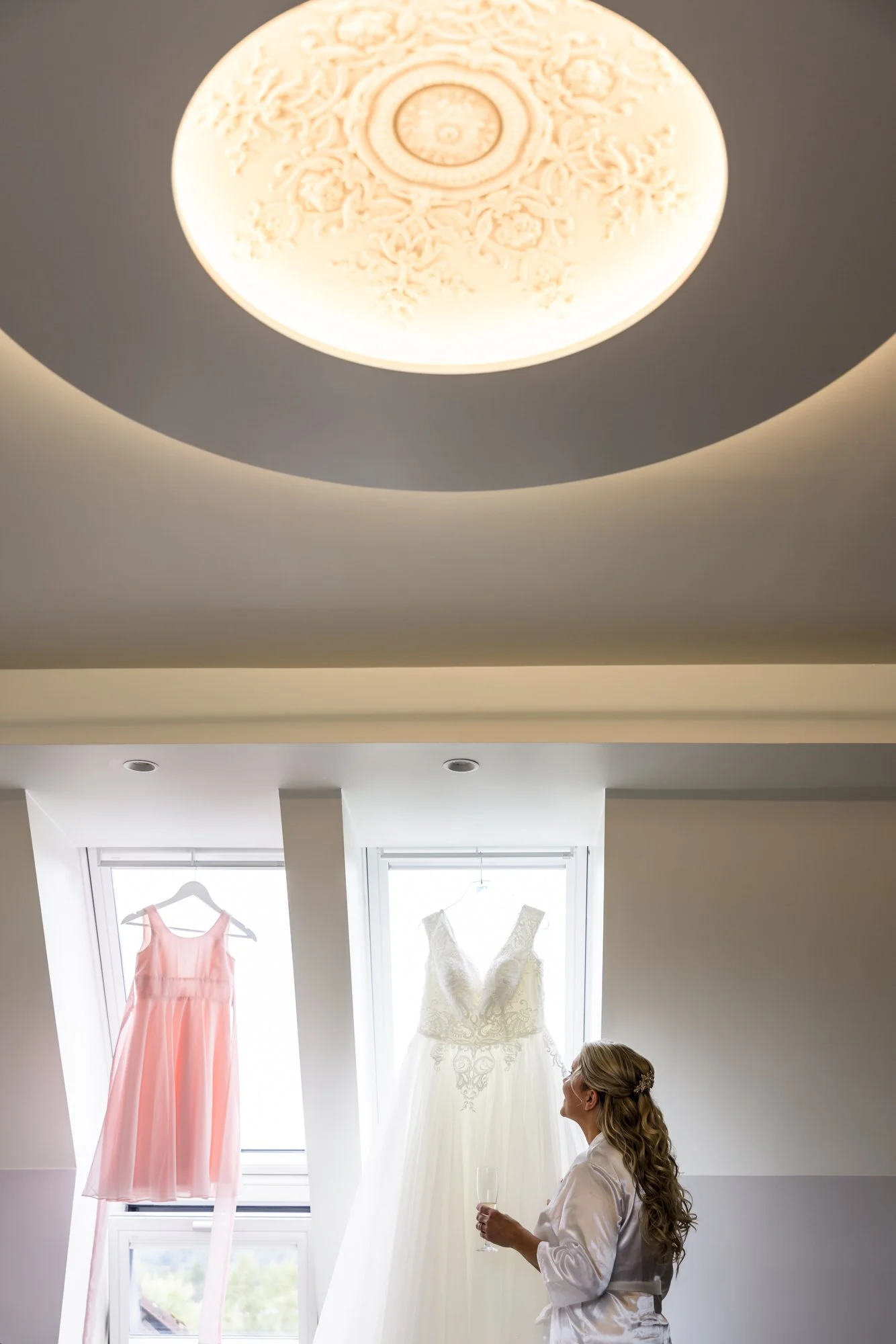 En kvinne ser på bryllupskjoler hengende opp i et rom.