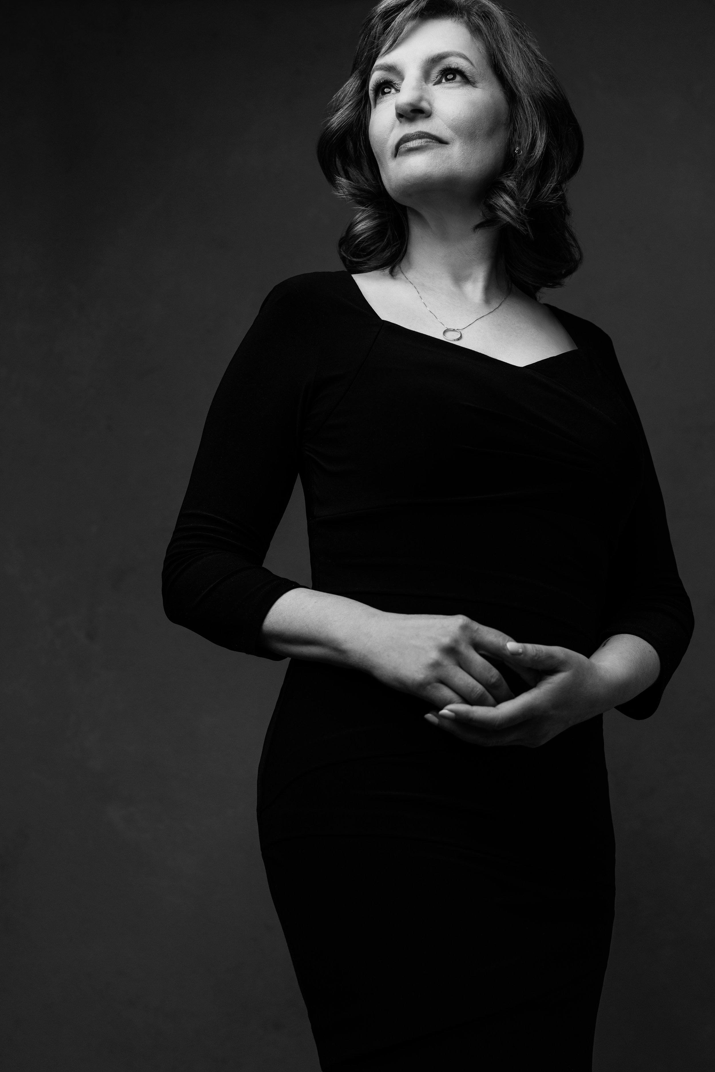 Black and white studio portrait of a woman in her 50s standing fully in her power