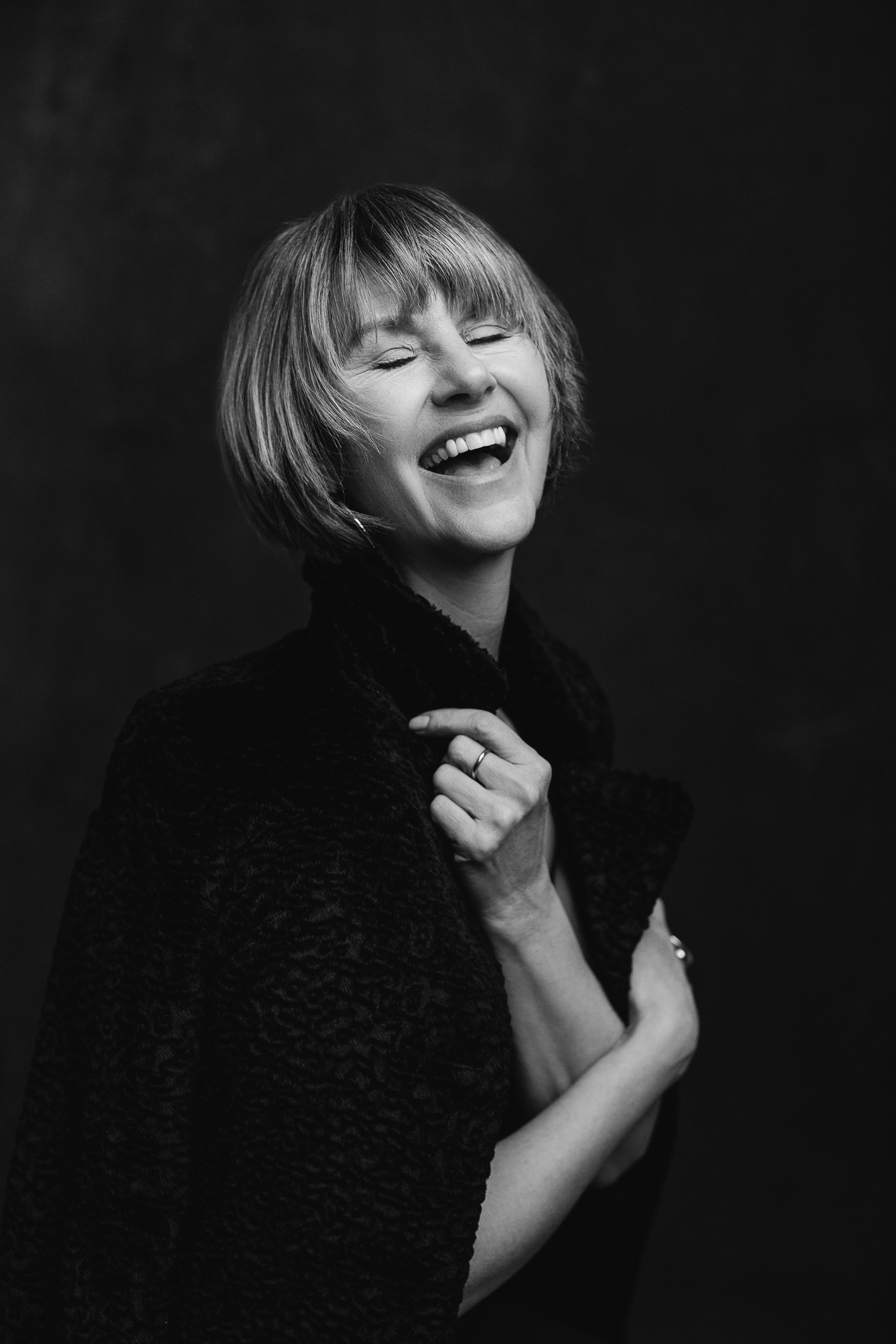 black and white editorial style portrait of a woman in her 60s laughing with joy celebrating her individuality