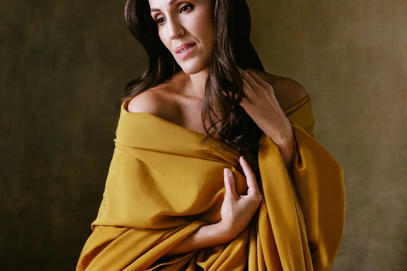 Quiet and soulful mood portrait of a woman in her 40s wrapped in yellow scarf self-reflecting on personal journey