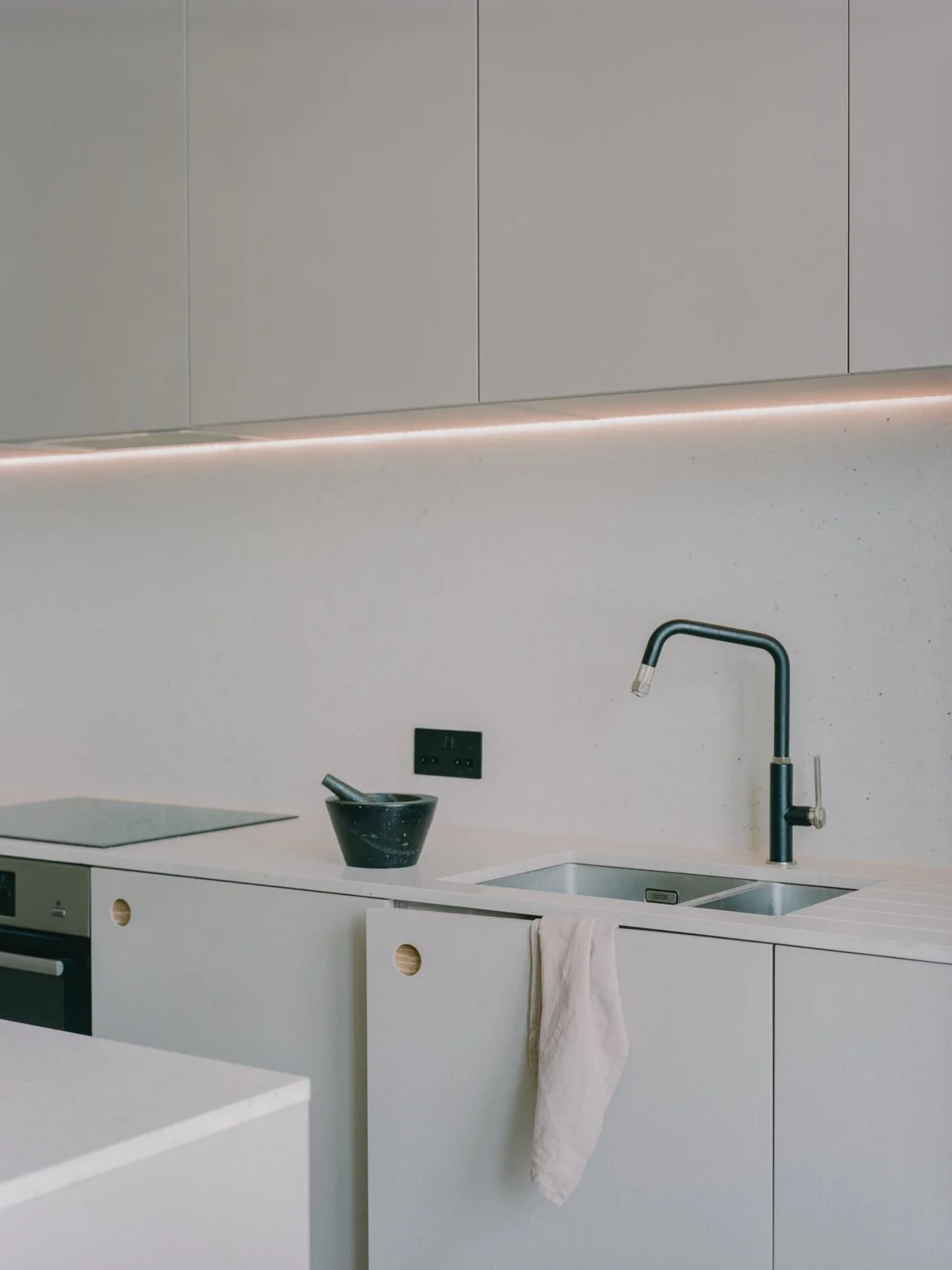 Modern kitchen with white countertops, black faucet, black bowl, and gray cabinets.
