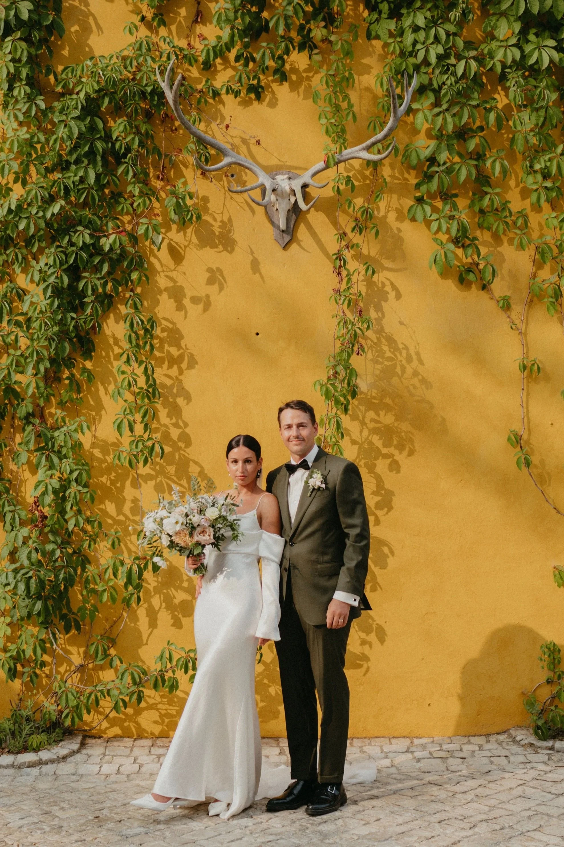 bride and groom portrait against yellow wall at Quinta de Sant'Ana wedding Mafra Portugal