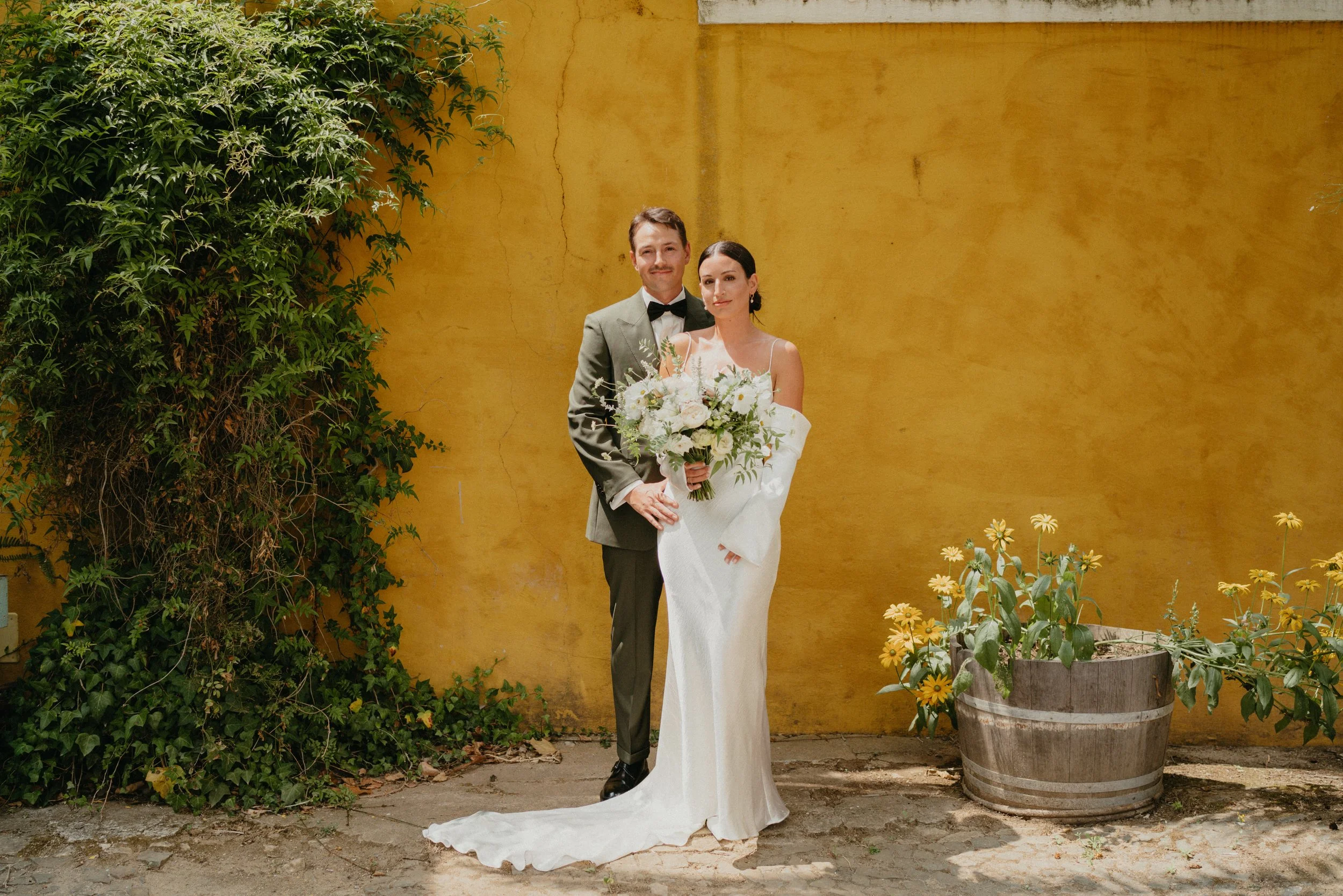 Bride and groom portrait at Quinta de Sant’Ana wedding venue in Mafra Portugal with yellow wall backdrop