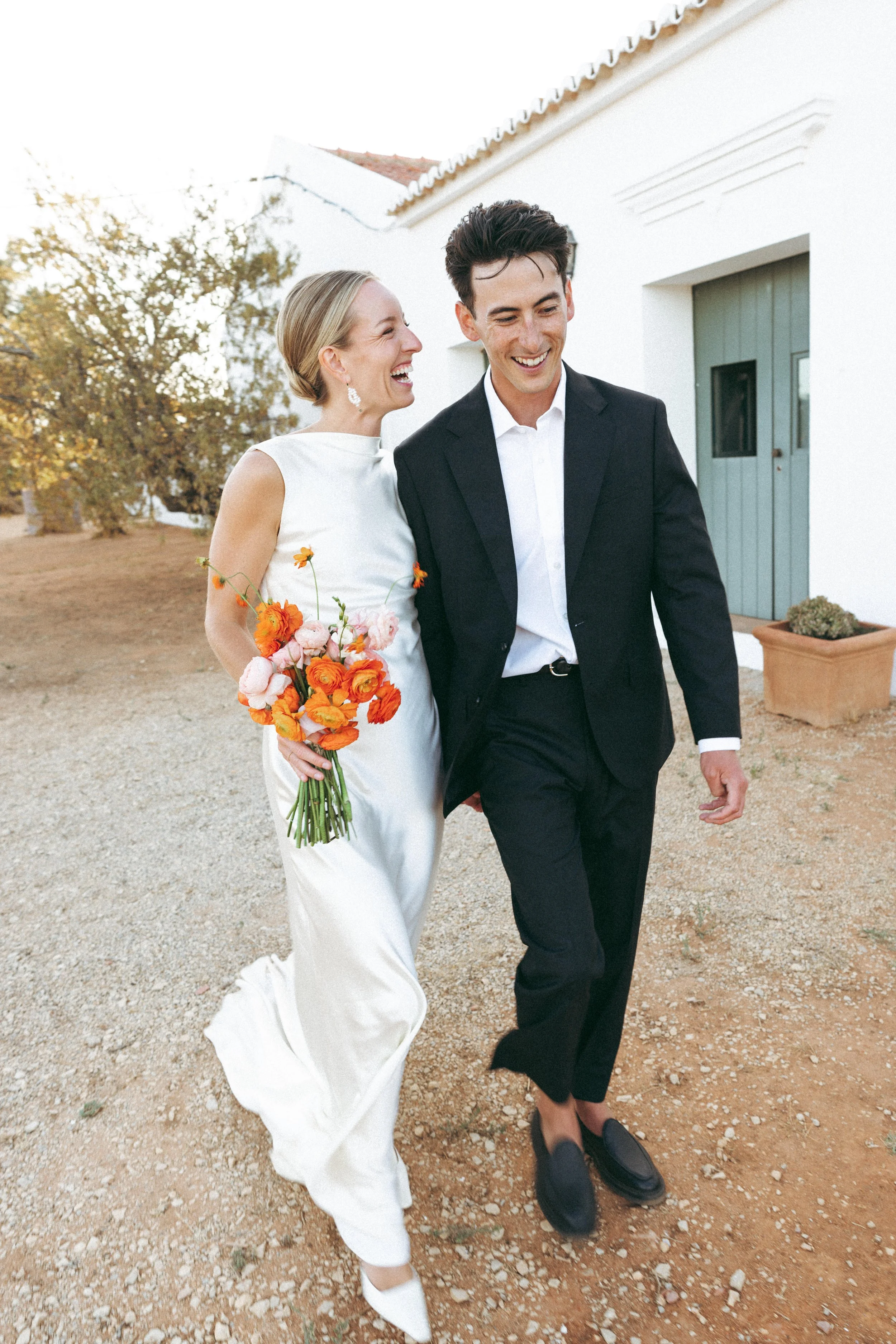 Bride and groom walking together with flowers during their intimate wedding at Morgado do Quintão vineyard in the Algarve.