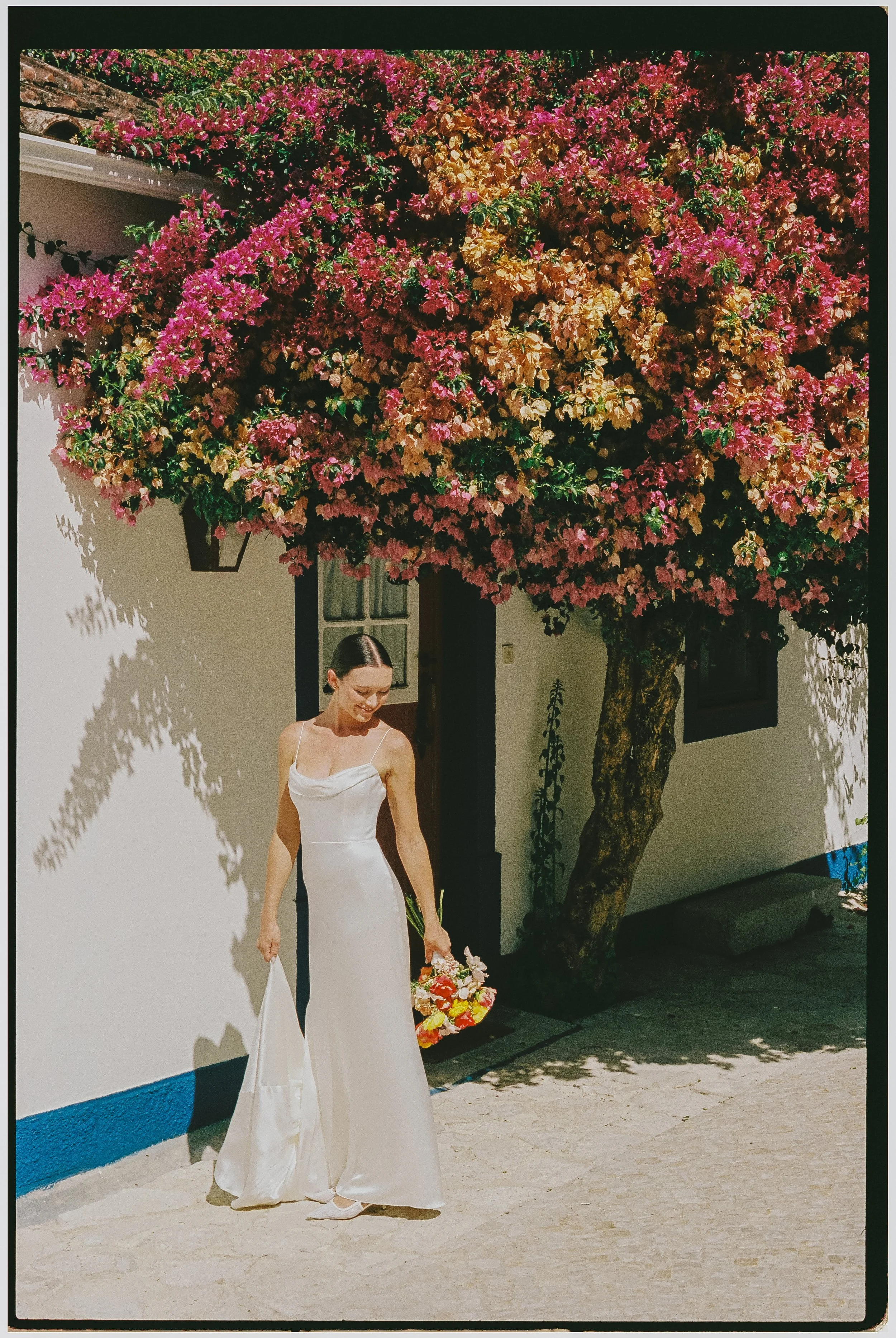 Bride standing under bougainvillea flowers during an intimate destination wedding in Portugal