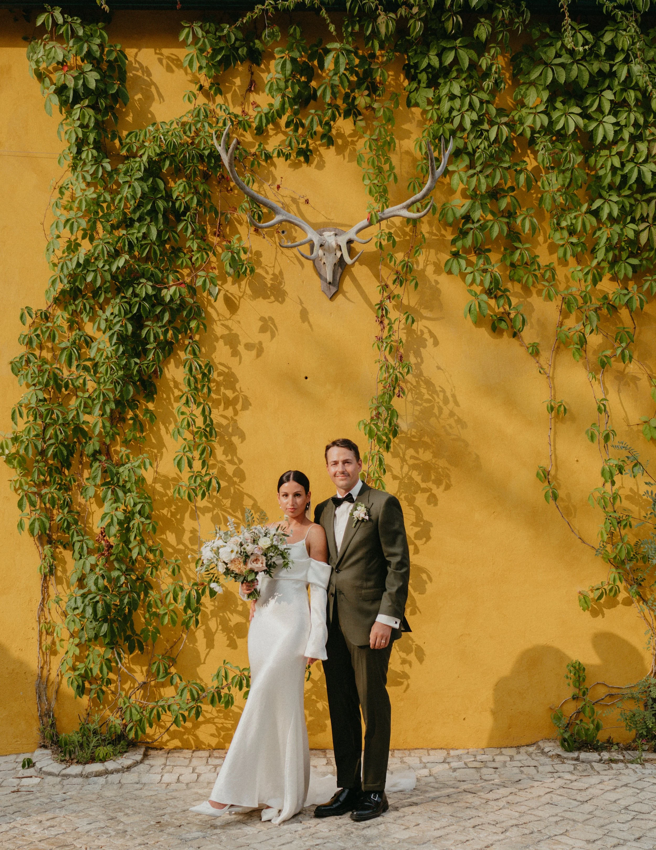 bride and groom portrait against yellow wall at Quinta de Sant'Ana wedding Mafra Portugal