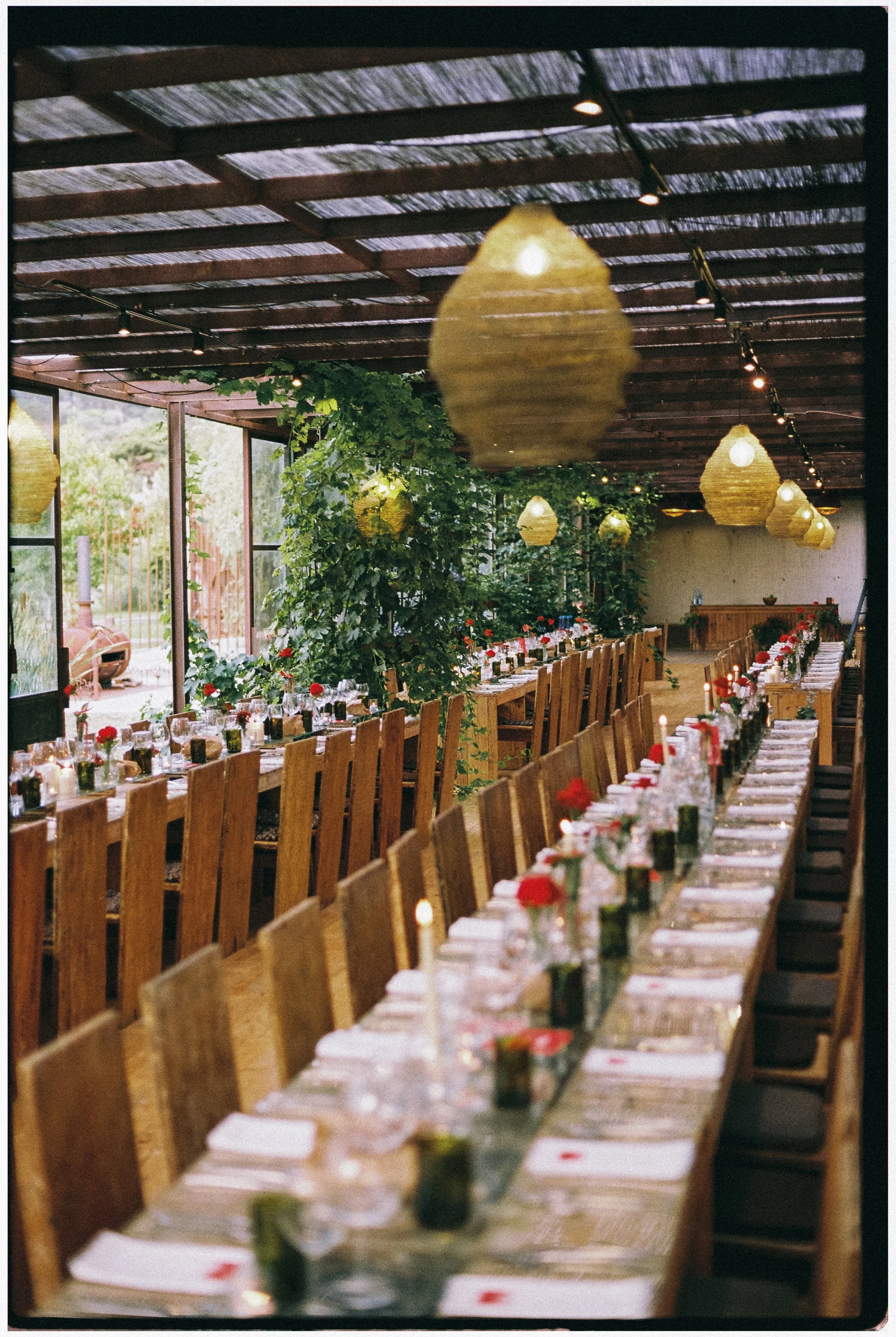 wedding dinner inside Rio do Prado greenhouse with hanging lanterns and long tables Óbidos Portugal