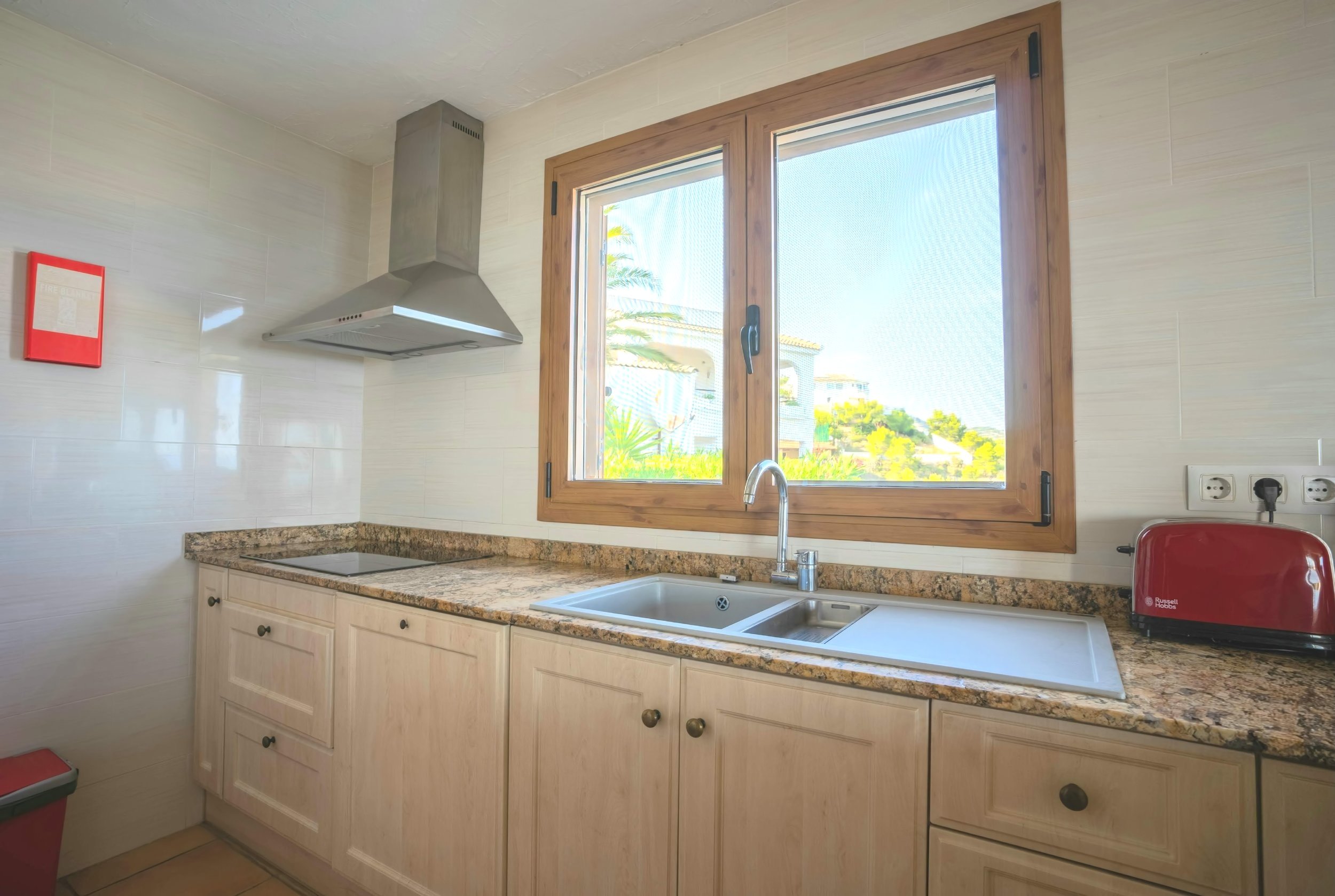 Moderna cocina con ventana con vistas a la piscina, lavavajillas integrado y placa eléctrica
