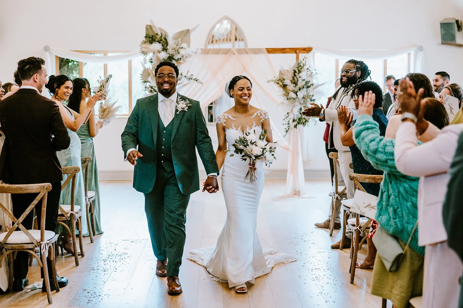newlywed couple walking down the aisle with guests cheering