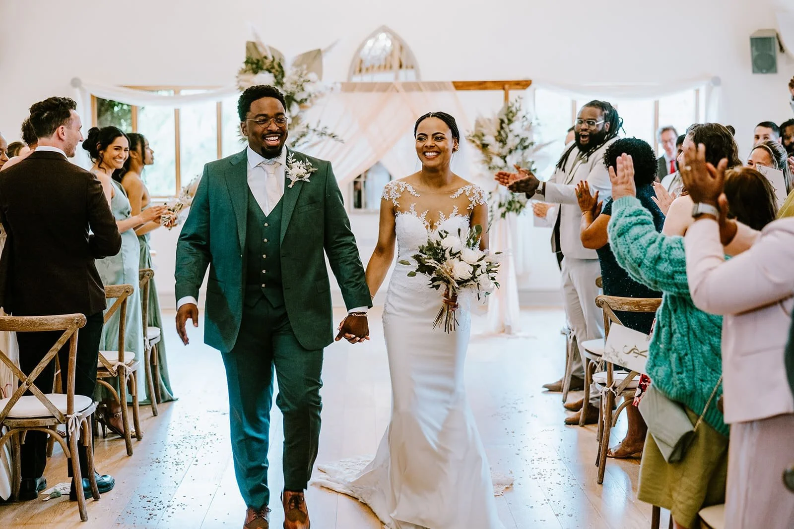 newlywed couple walking down the aisle with guests cheering
