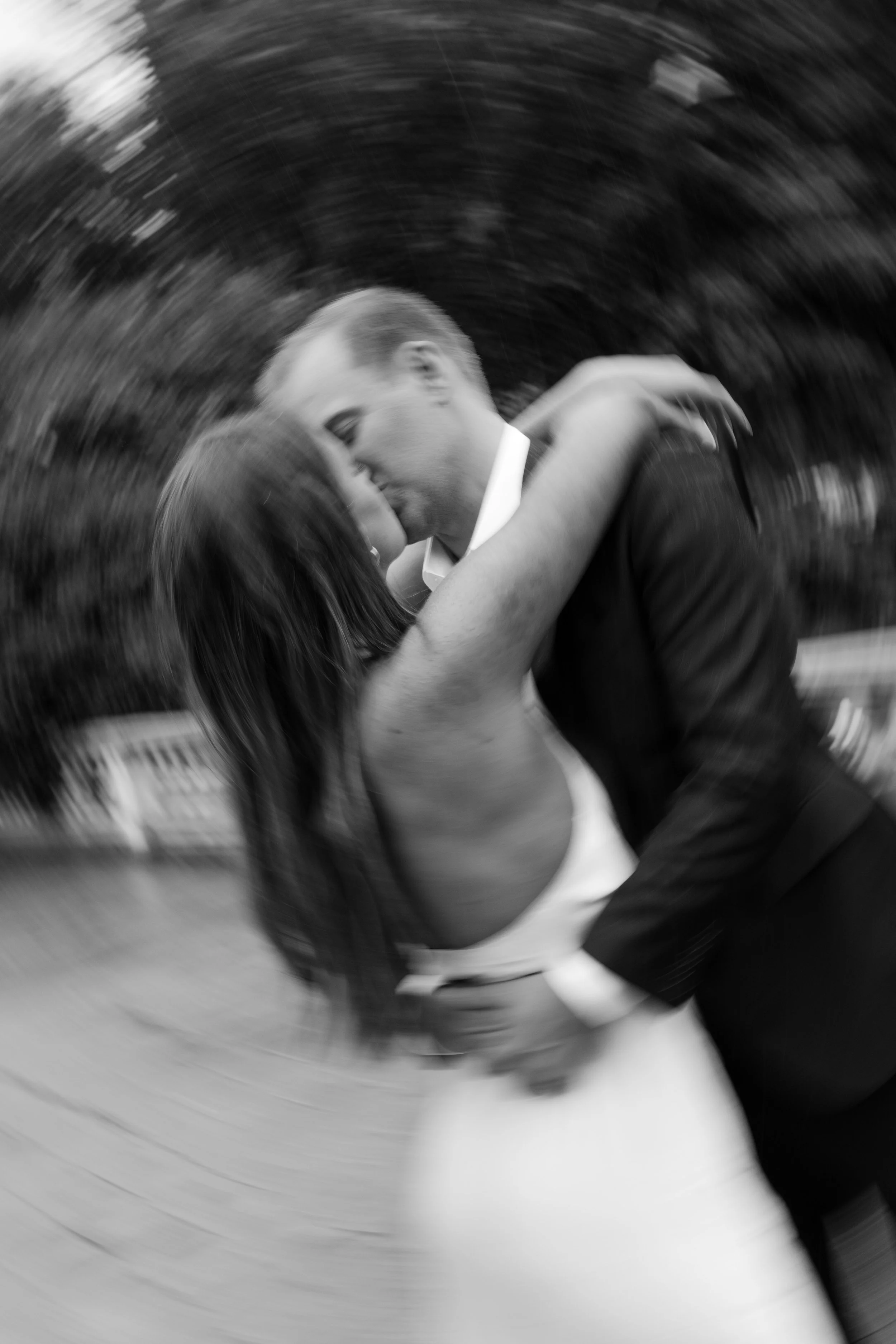 A black and white photo of a couple kissing, with a blurred background and motion effects.