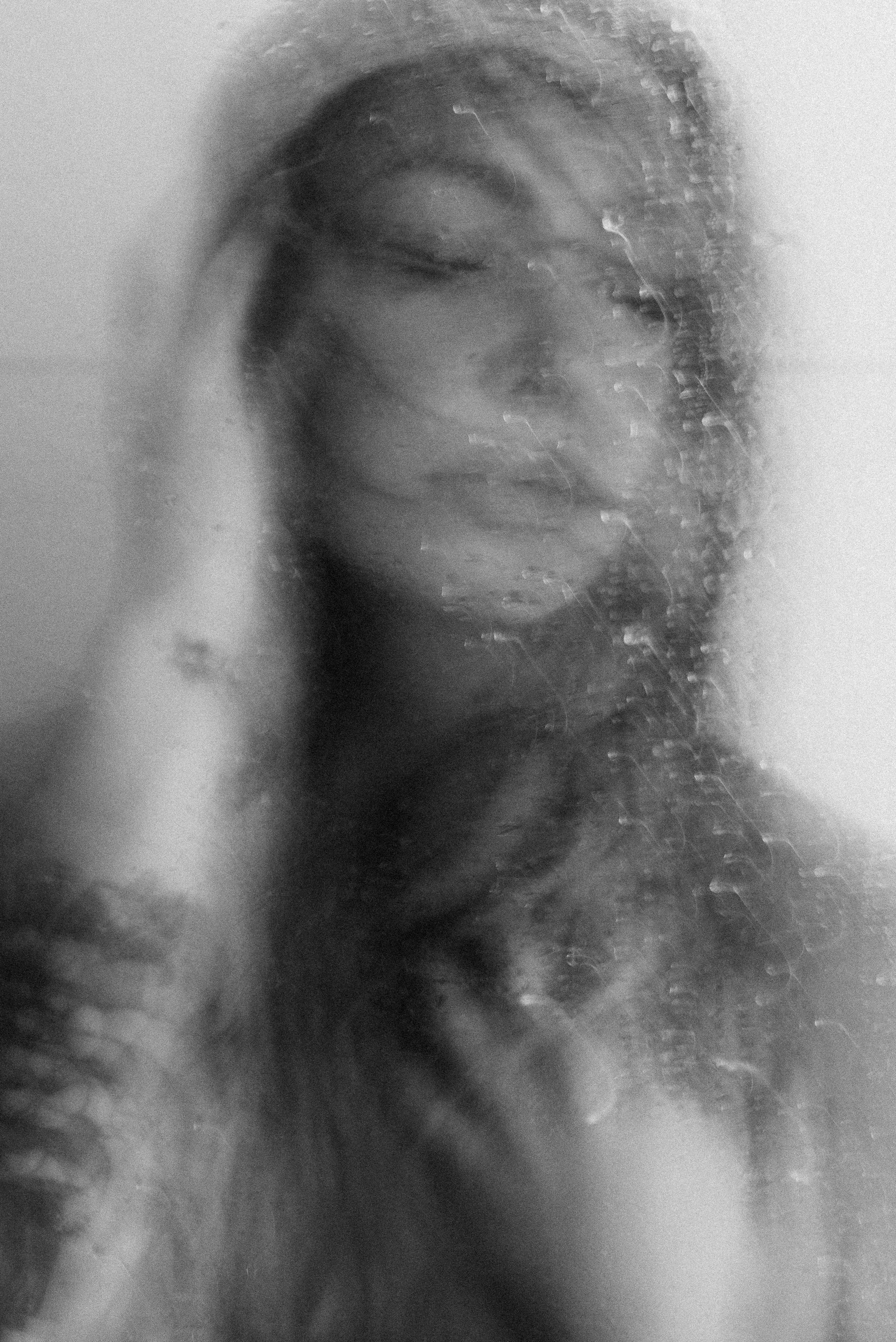 Blurry black-and-white photo of a woman's face with closed eyes, with a distorted effect.