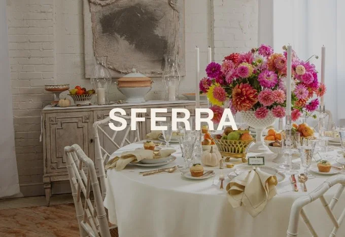 Elegant dining table set with white tablecloth, floral centerpiece, candles, and place settings in a bright, modern room.