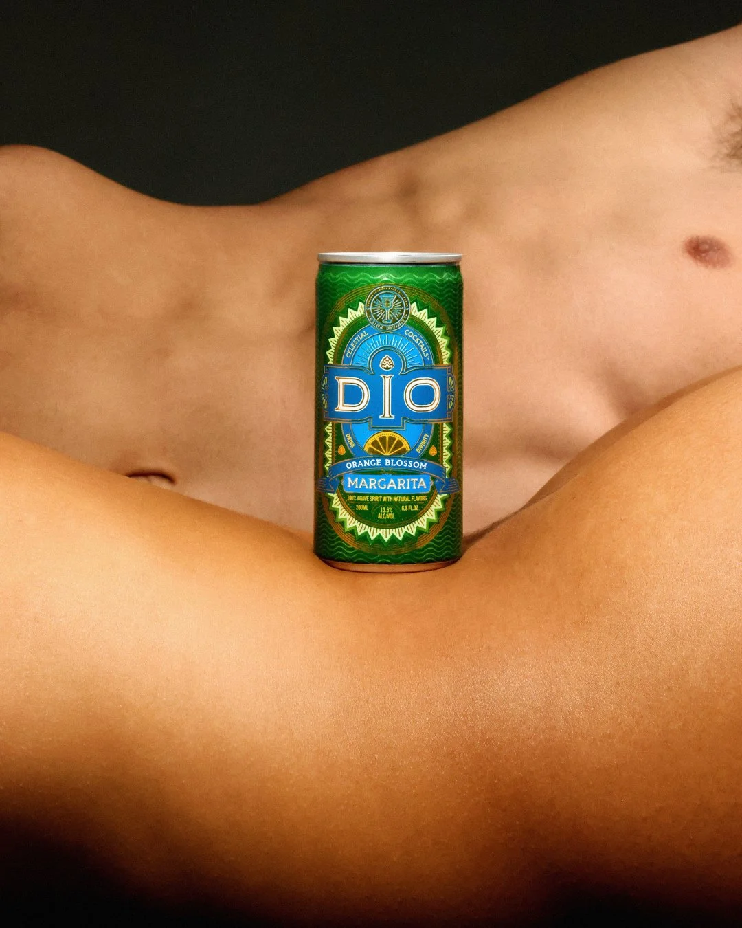A can of Dio Orange Blossom Margarita drink rests on a person's bare leg, with the person's torso and shoulder visible in the background.