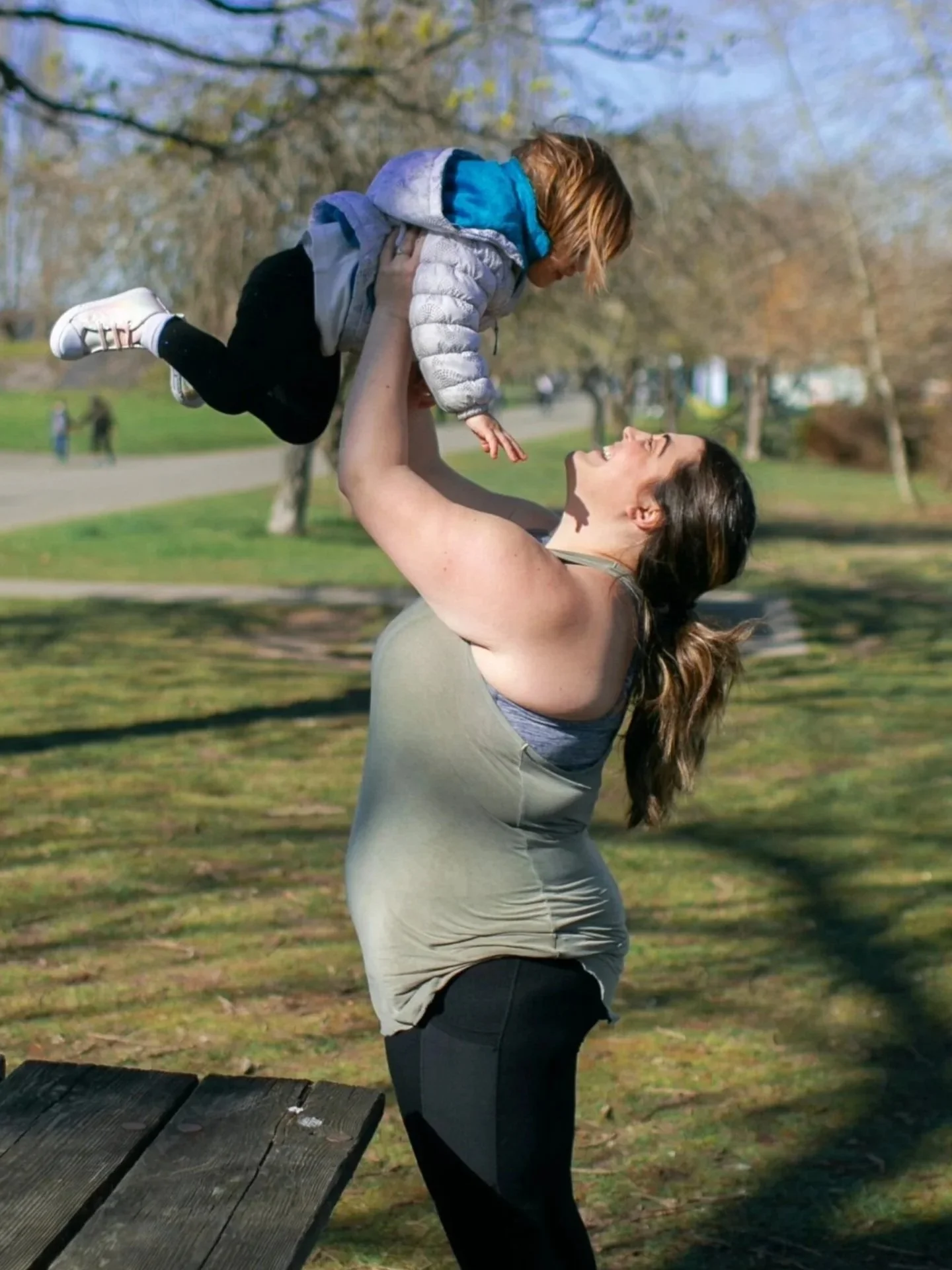 Seattle Mom uses her Pilates training to lift her toddler in a park.