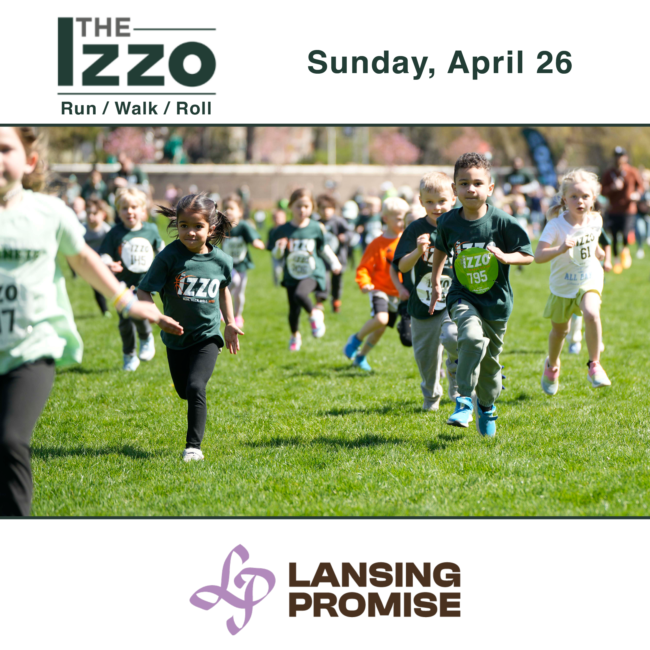 Children running in a race outdoors during the Lansing Promise event on April 26, wearing dark green shirts with the event logo, on a grassy field with a crowd and trees in the background.