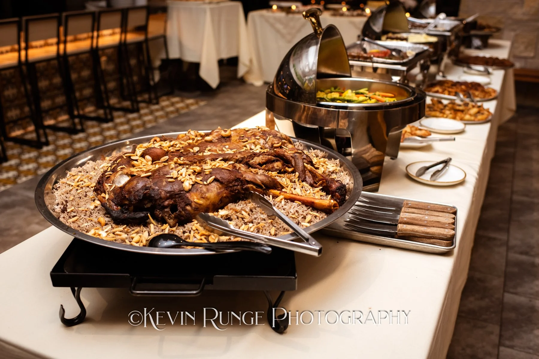 Buffet table with roasted meat, vegetables, and various dishes at a restaurant or event.