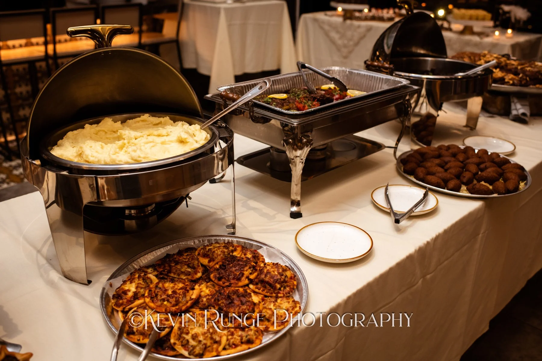 Buffet table with mashed potatoes, meatloaf, meatballs, and other dishes in chafing dishes at a restaurant or event.