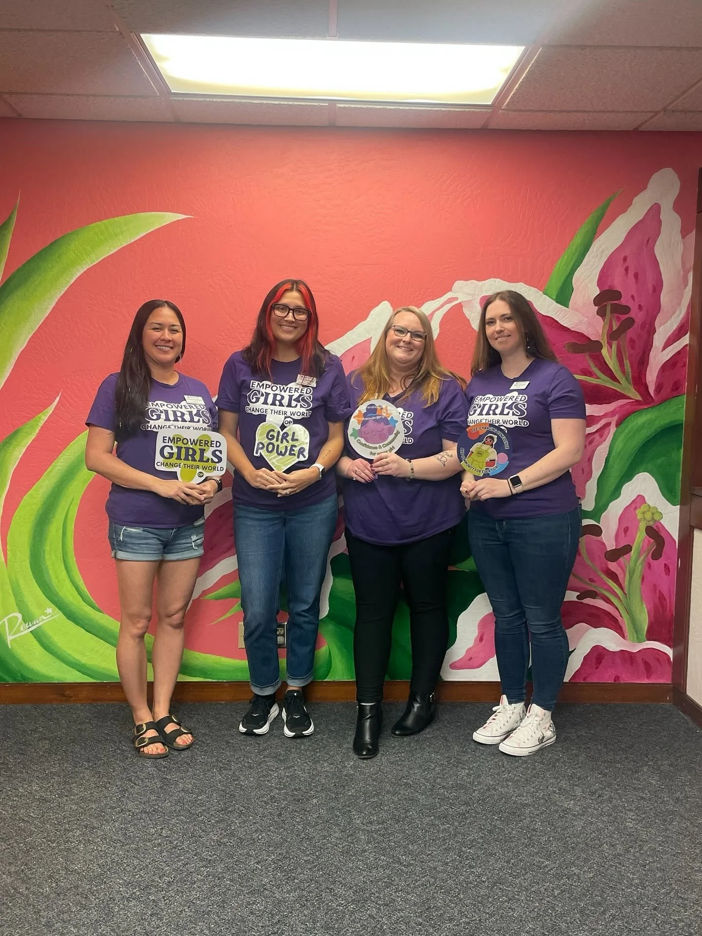 Four of Ophelia's Place team members wearing matching purple shirts and posting with signs