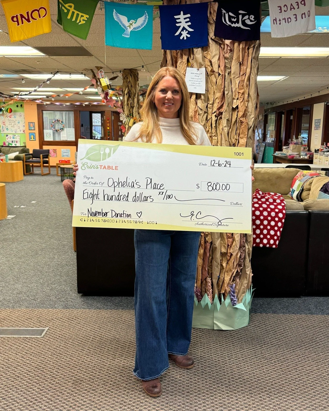 Woman holding giant check made out to Ophelia's Place