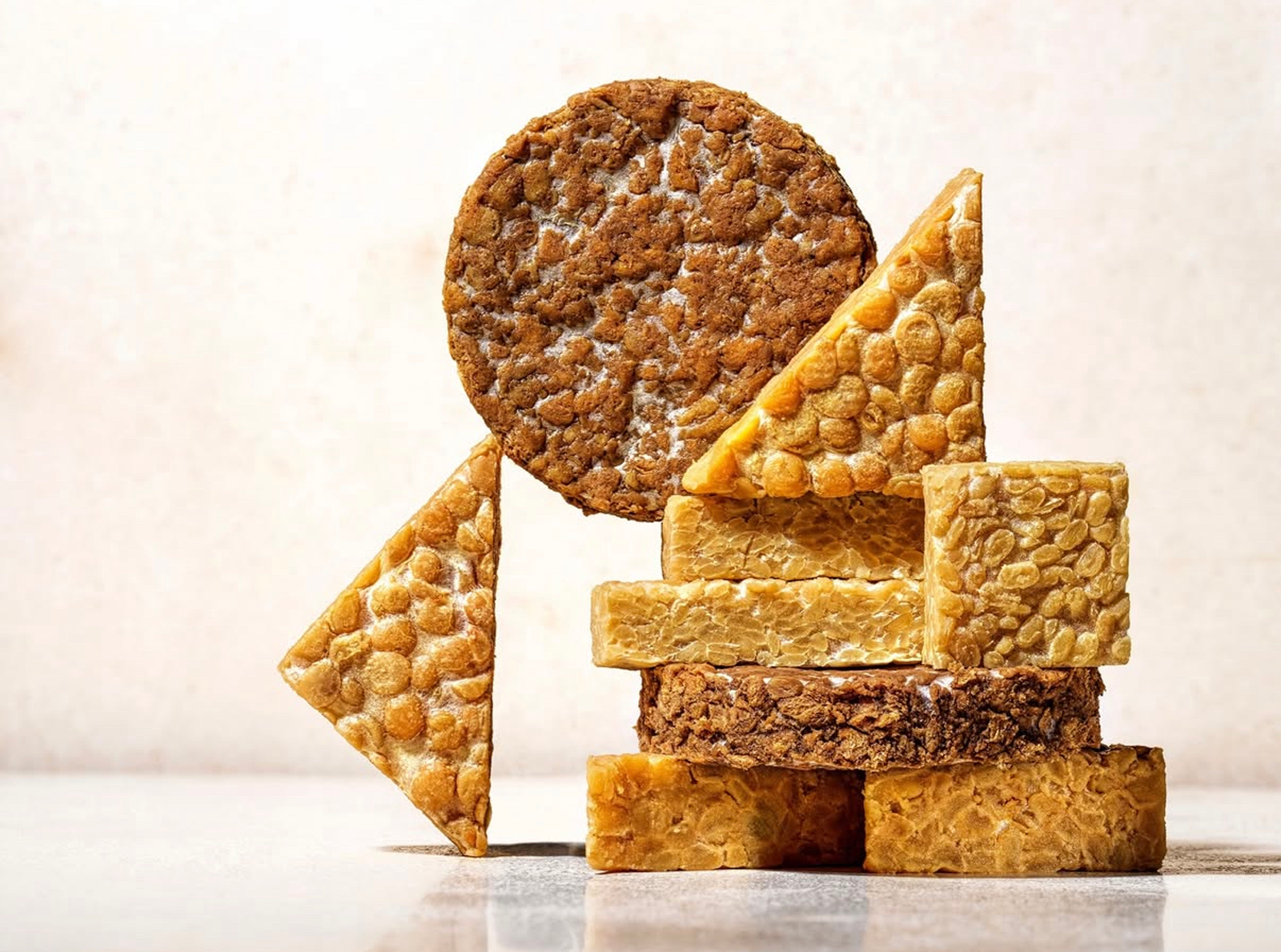 An assortment of various types of caramel, peanut, and nut-based candies stacked on a flat surface.