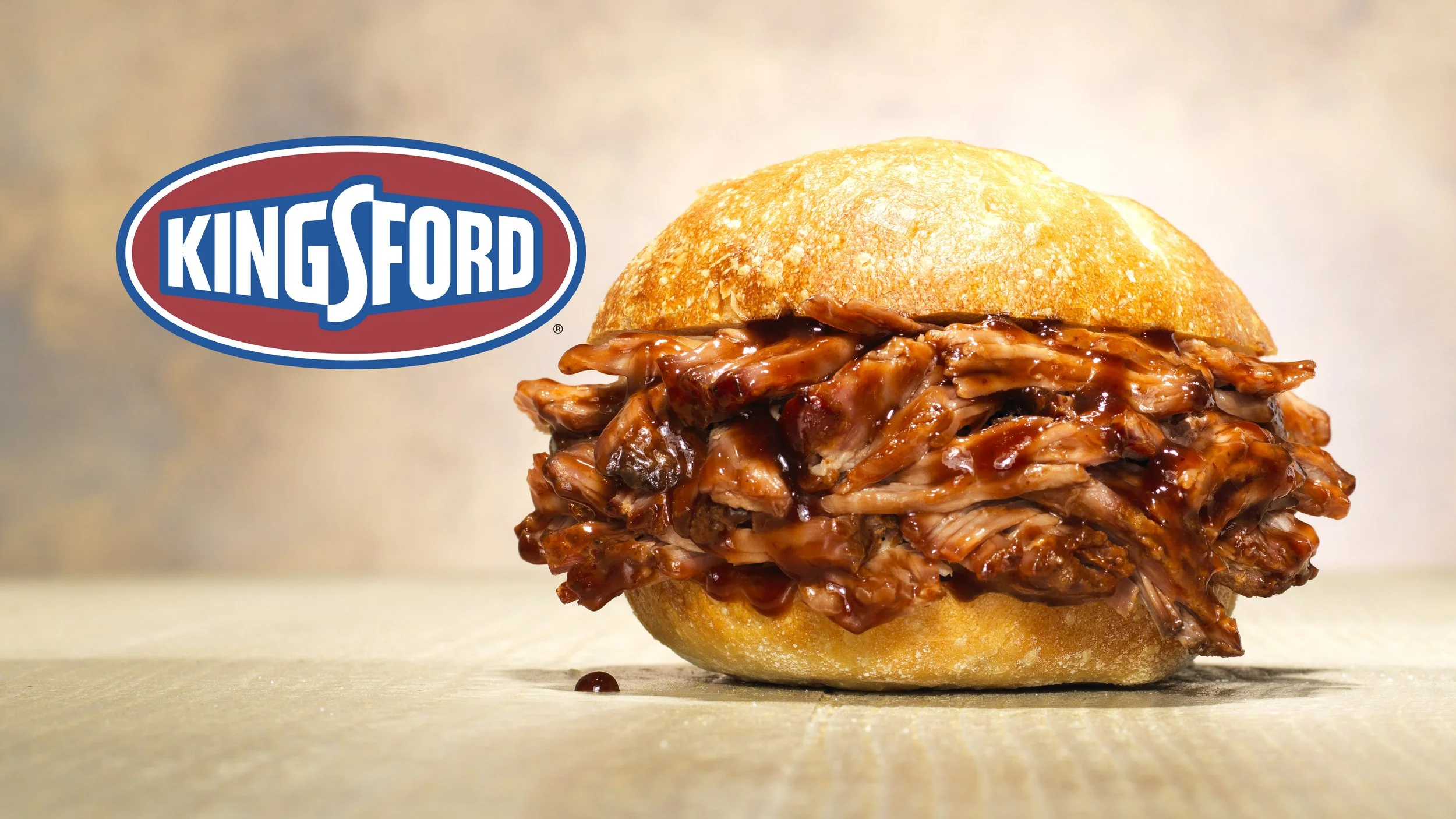 A barbecue pulled pork sandwich with a bun, barbecue sauce, and shredded meat, with a King's Ford logo in the background.