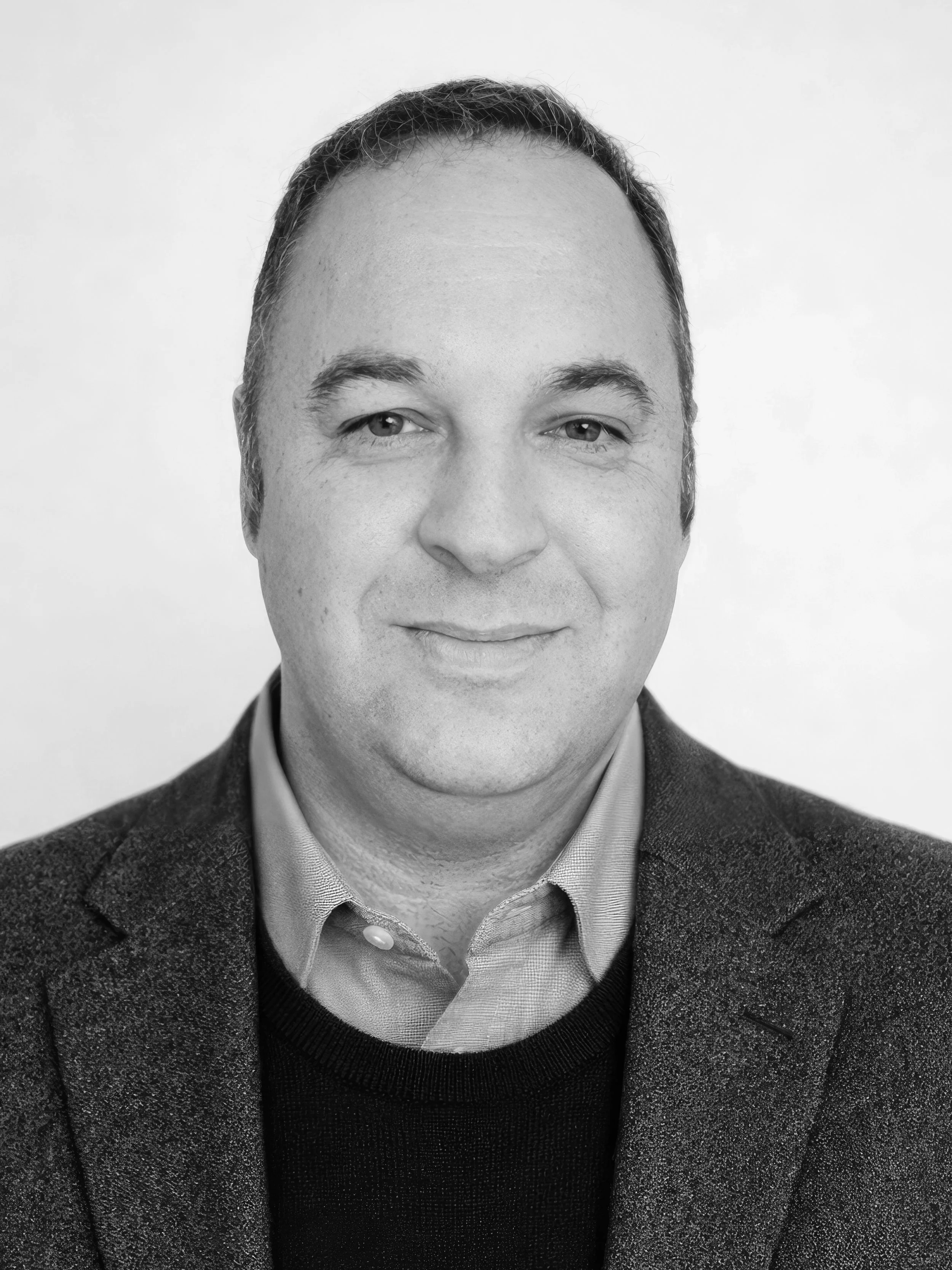 Black-and-white author headshot of Nicholas Taylor wearing a blazer and collared shirt, facing the camera against a plain background.