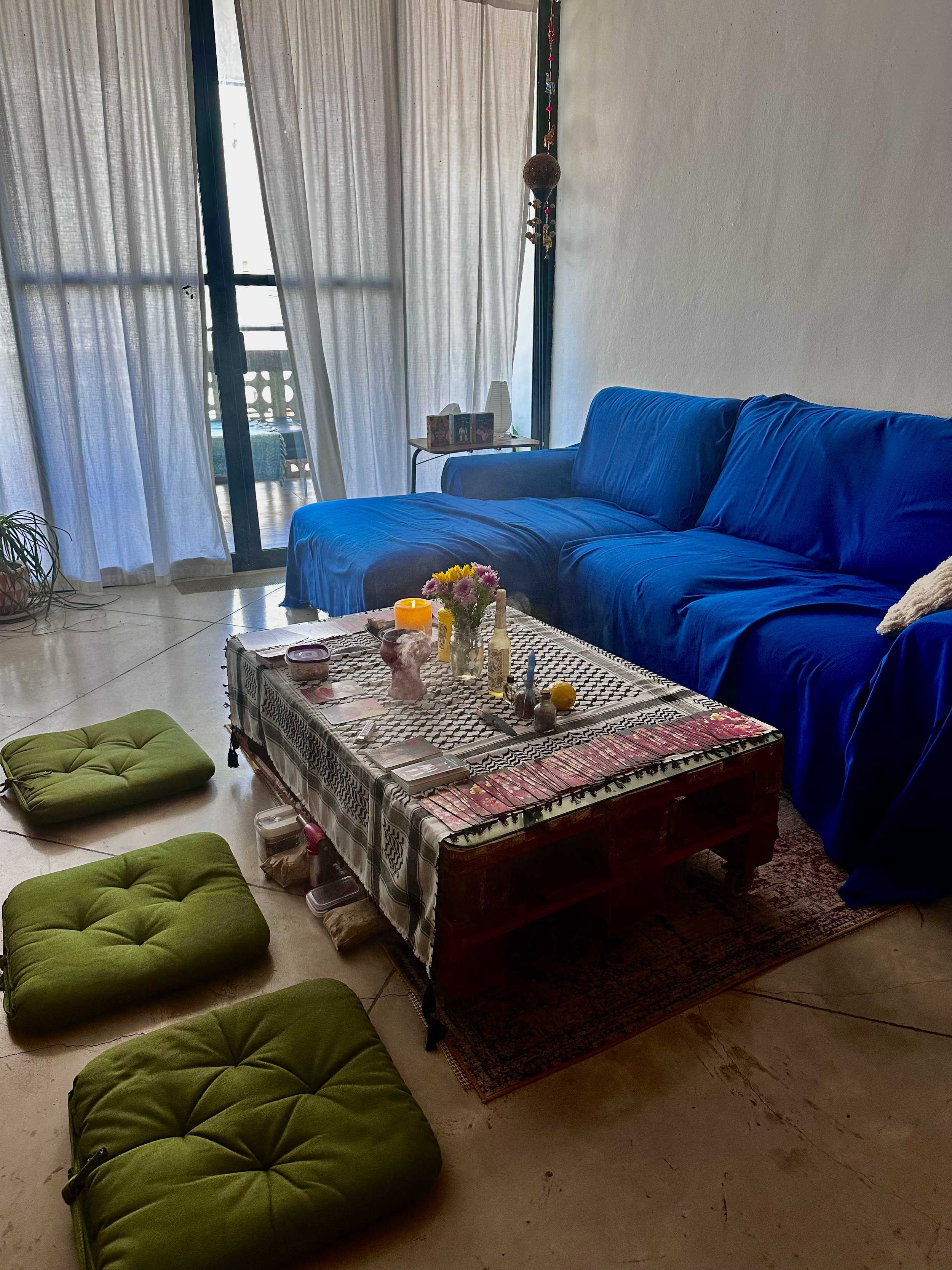 Living room with a blue couch, a coffee table with various objects, and green floor cushions.