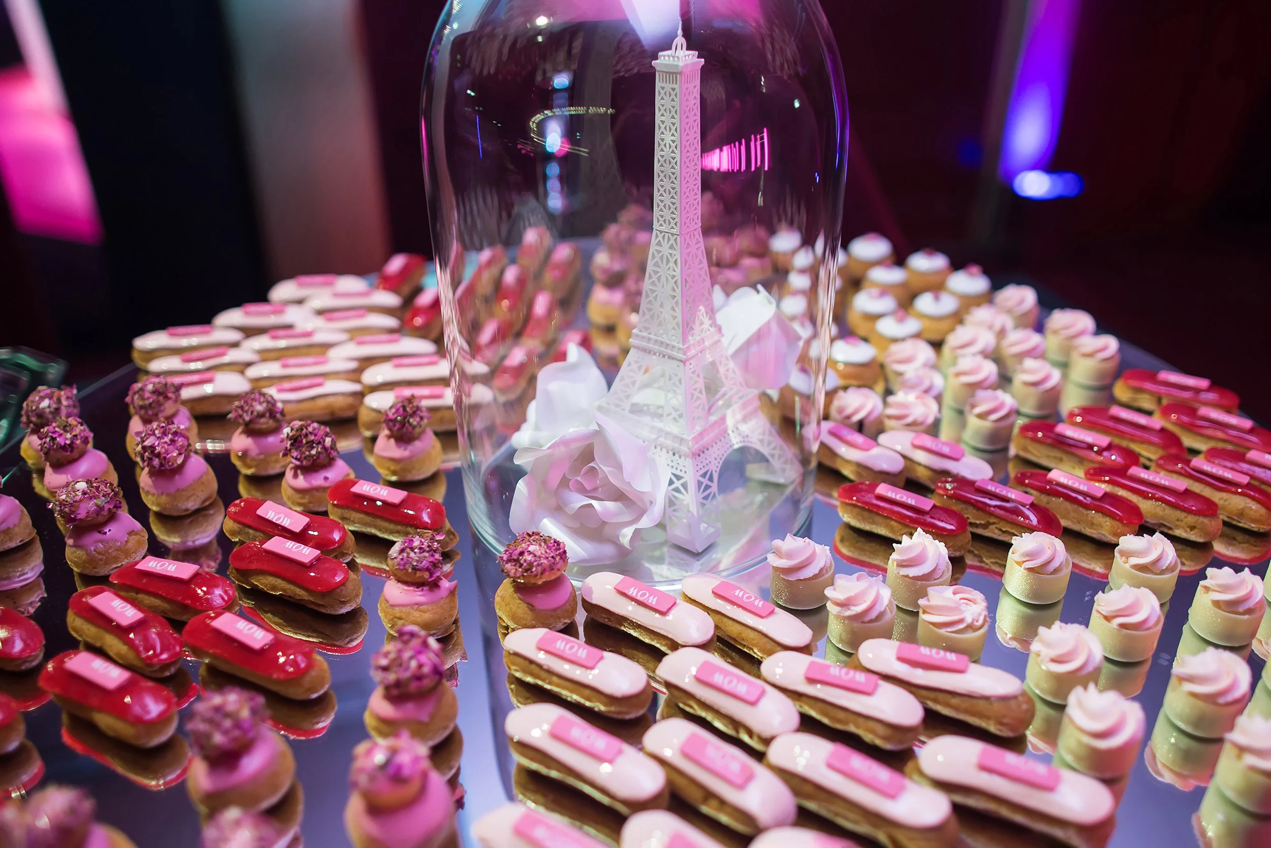 White paper Eiffel Tower and sculpted paper roses presented under a glass dome, set on a mirrored catering table