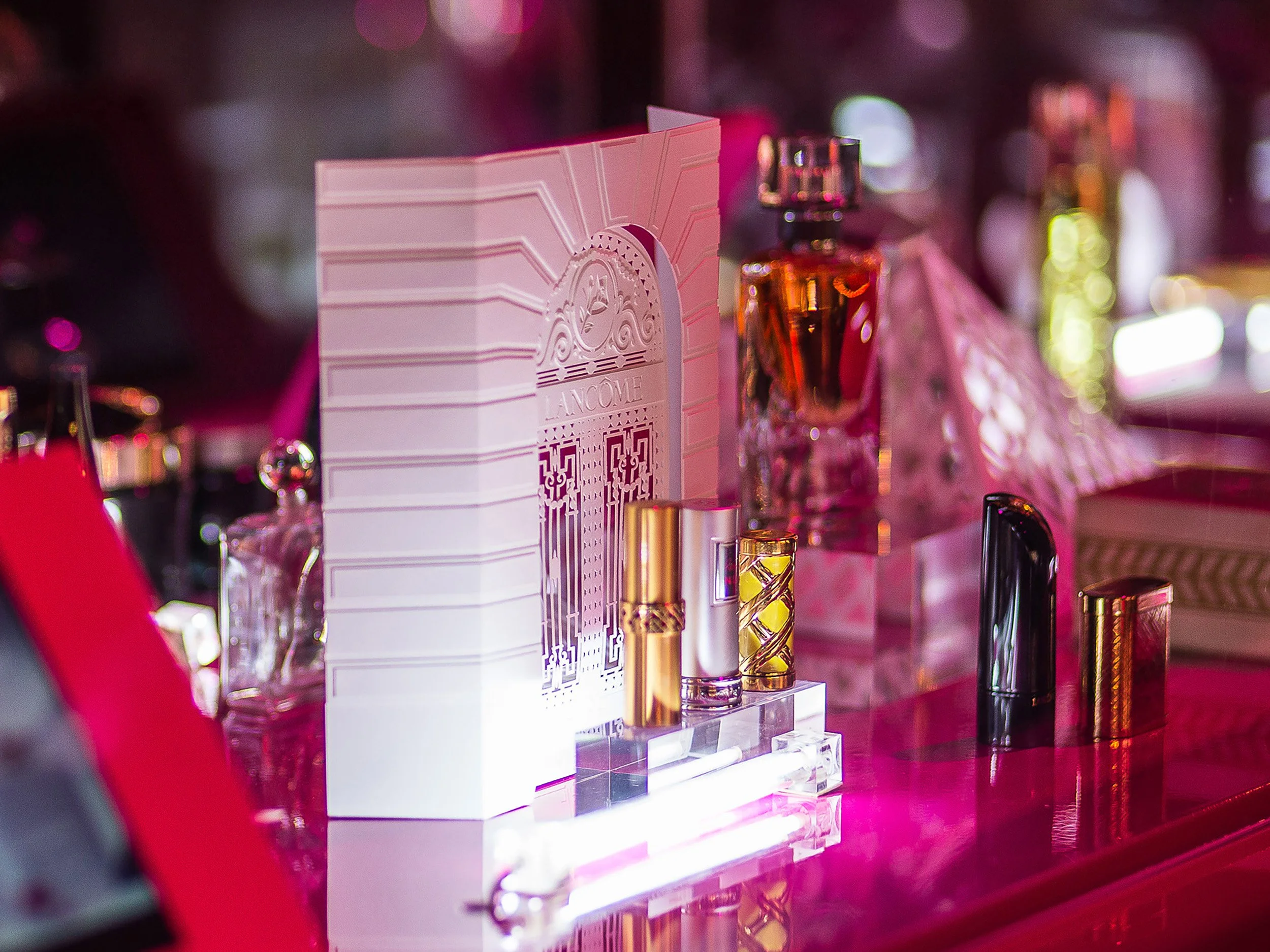 White paper architectural façade with Lancôme products under pink event lighting