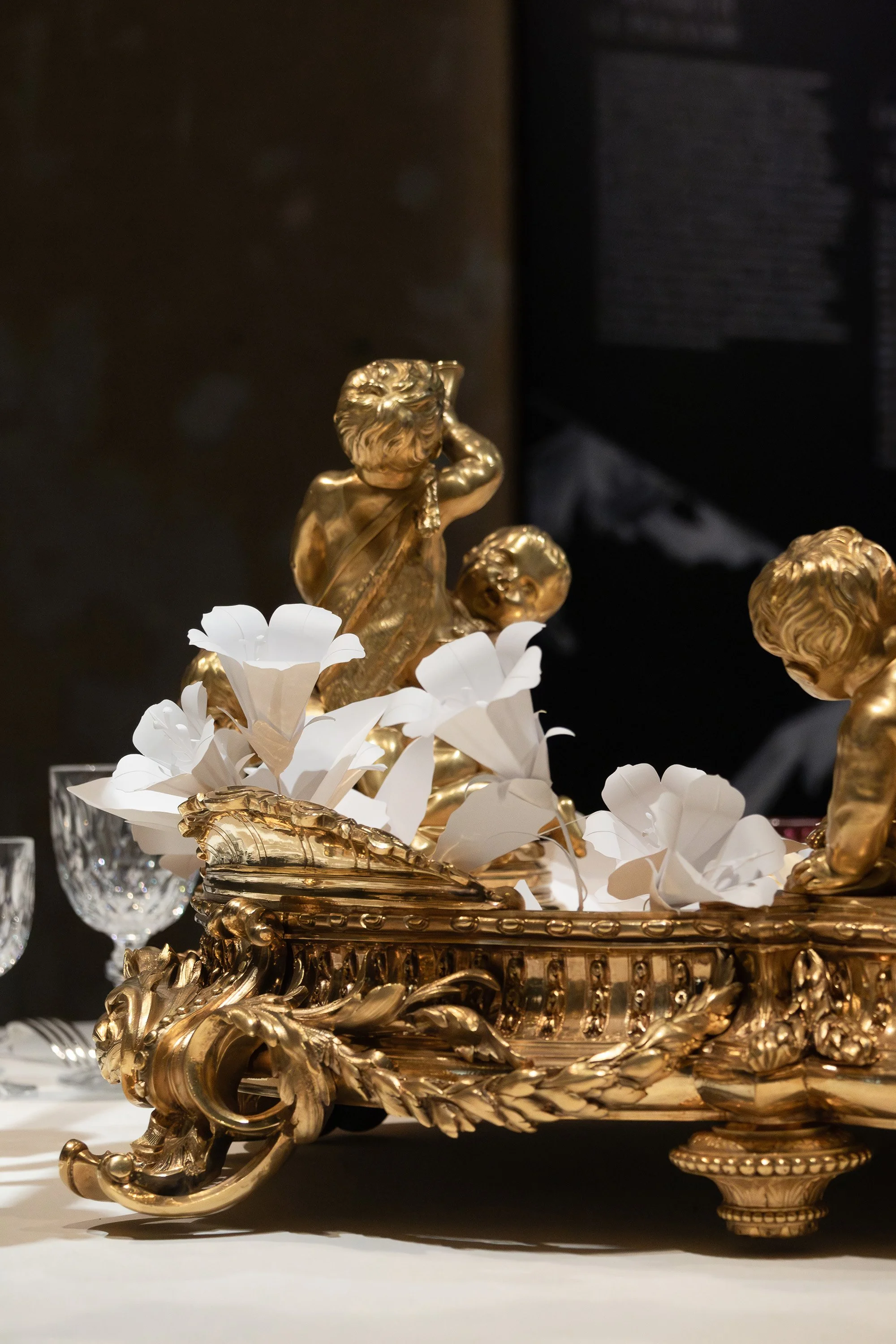 Detail of the ornate gilded Christofle jardinière with white paper bindweed flowers extending outward, exhibition table installation at the Musée des Arts Décoratifs, Paris.