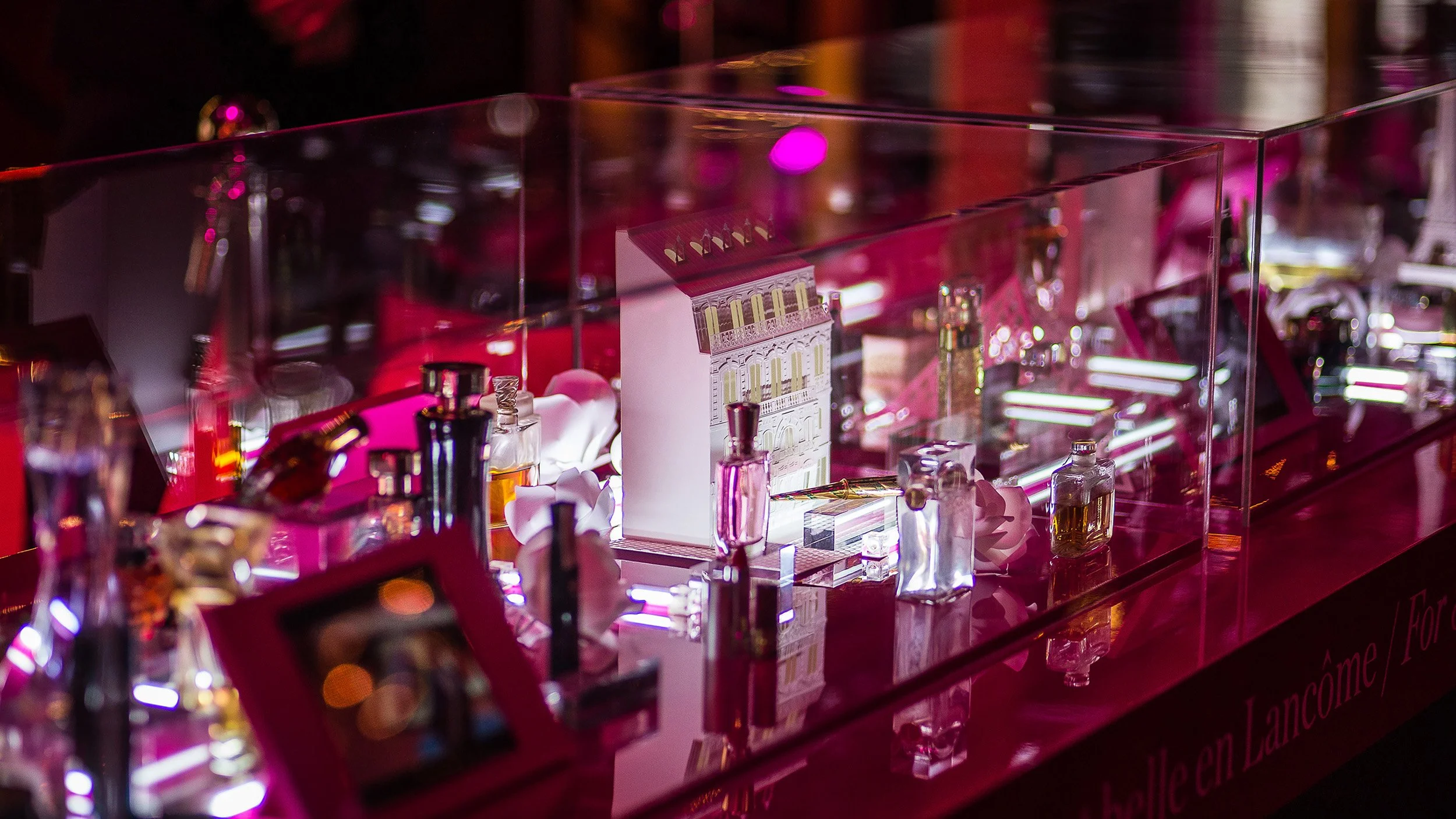 Miniature white paper Haussmann-style Parisian building with zinc rooftops displayed under glass case, Lancôme 80th anniversary set design