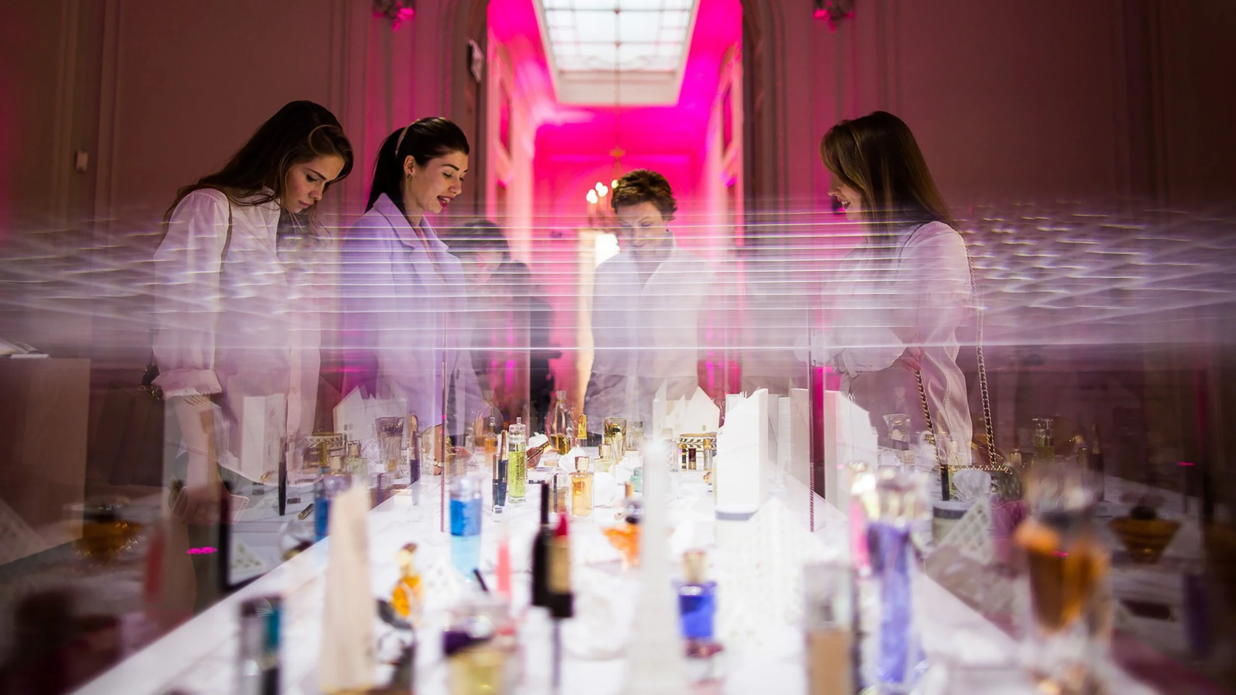 Guests observing the central white paper installation and fragrance display under bright lighting