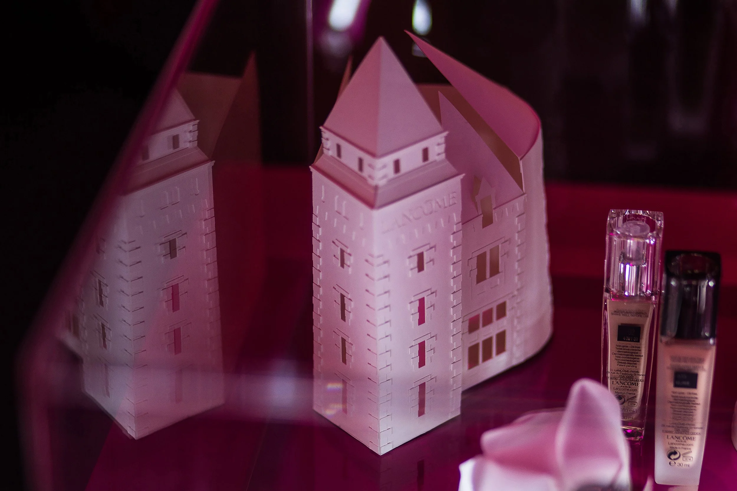 Handcrafted white paper model of Château Lancôme displayed with Lancôme products within the anniversary scenography