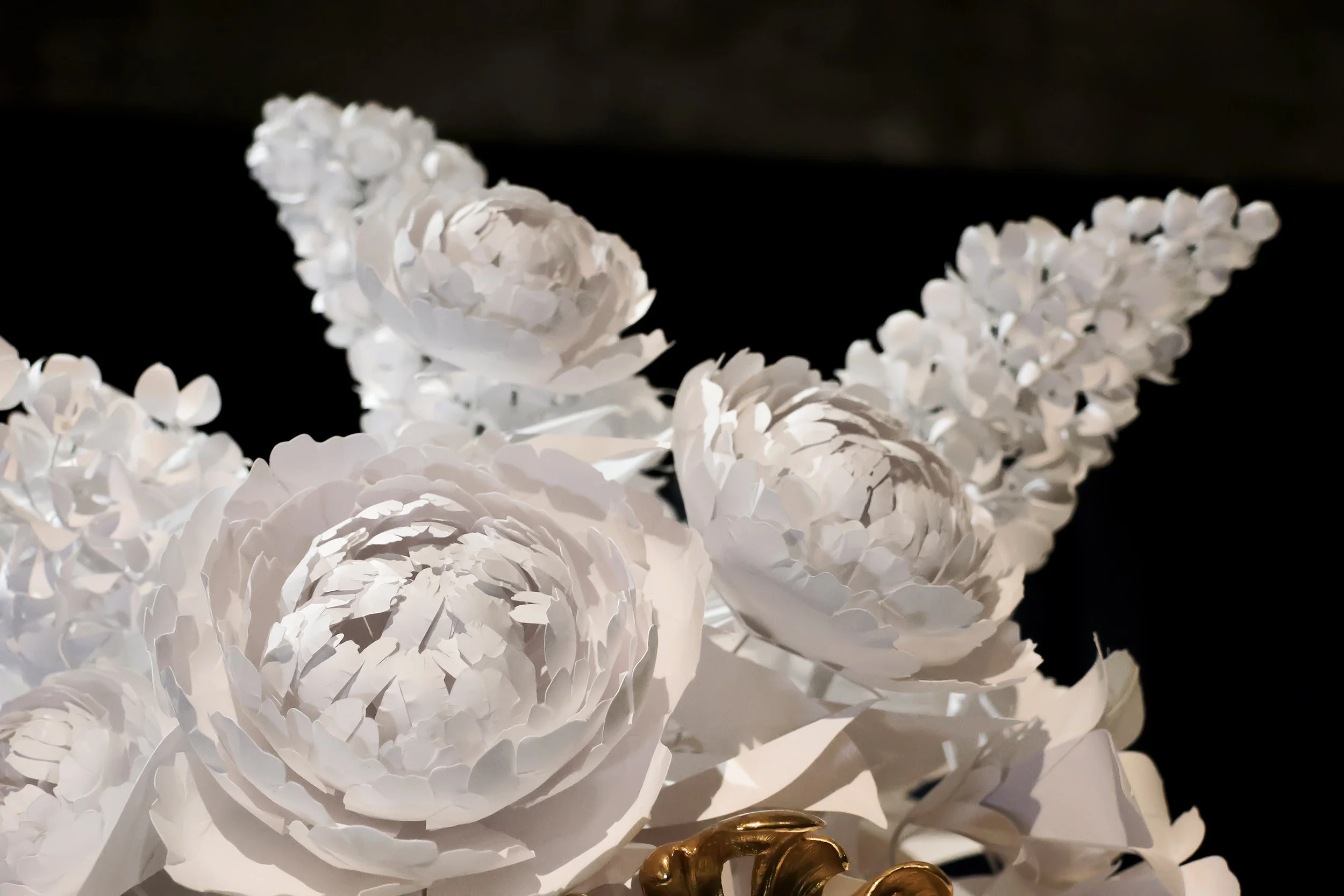 Close-up of white paper peonies and lilac branches in a sculptural floral installation for Christofle, Musée des Arts Décoratifs, Paris.