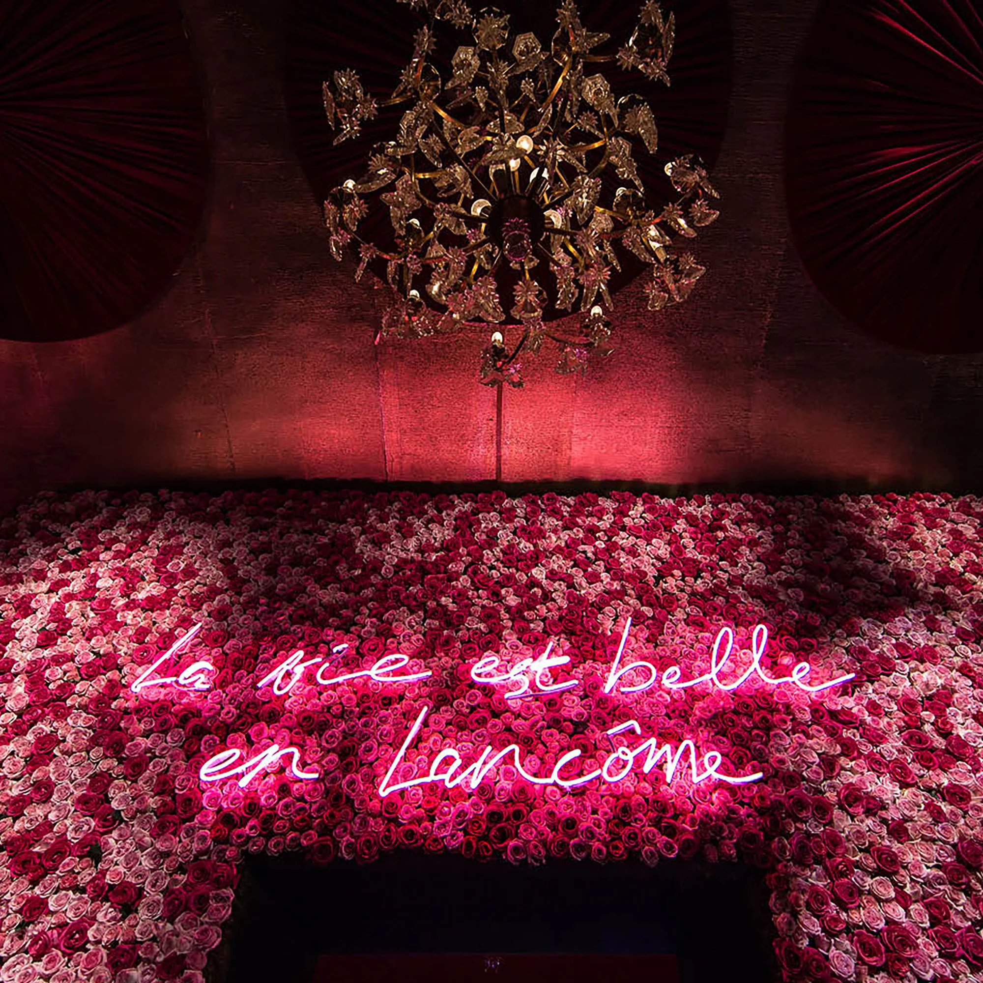 Rose wall installation with neon “La vie est belle en Lancôme” sign, 80th anniversary celebration scenography