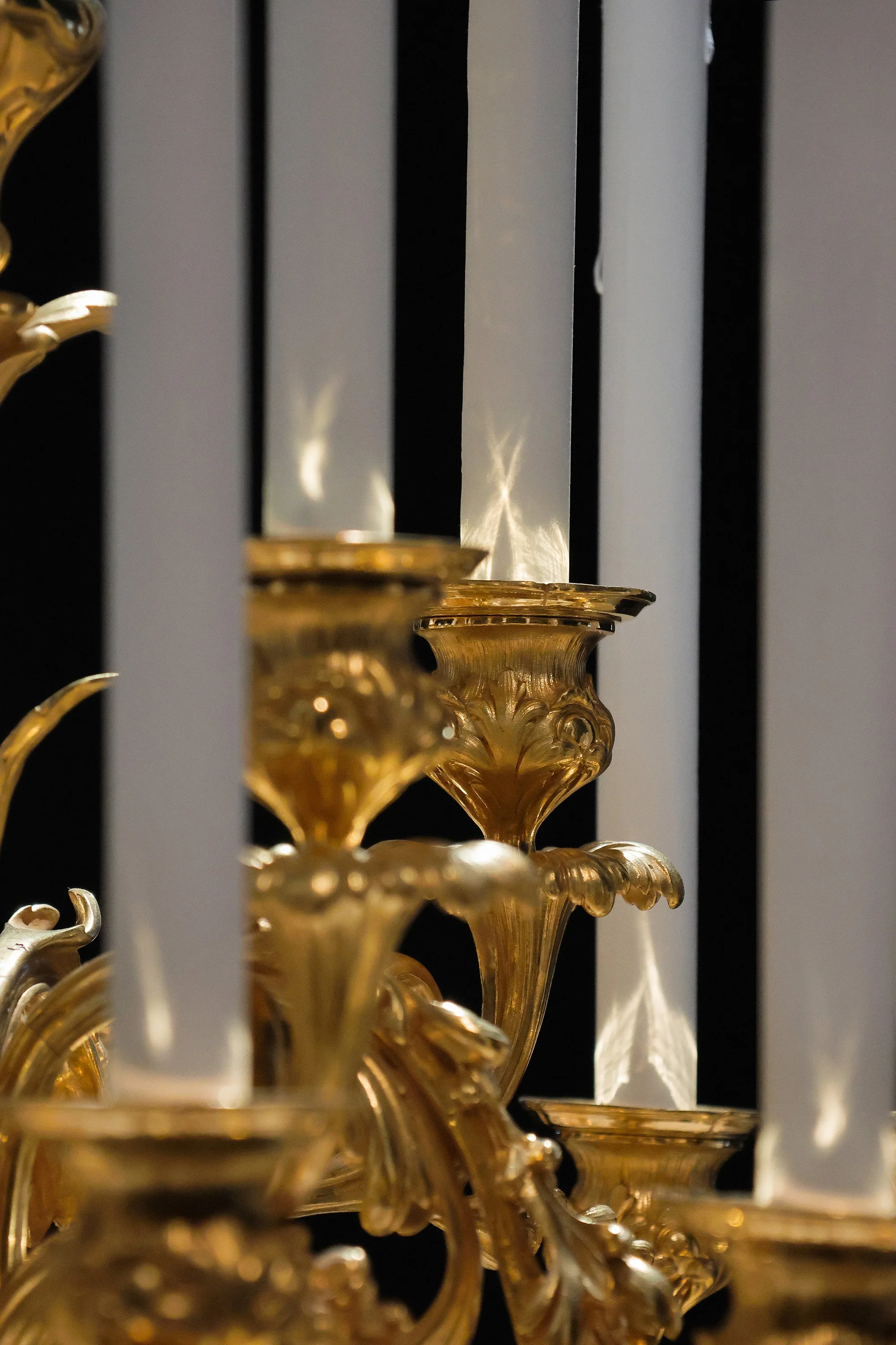 Detail of white paper candles reflecting light on gilded Christofle candelabra during exhibition at the Musée des Arts Décoratifs, Paris.
