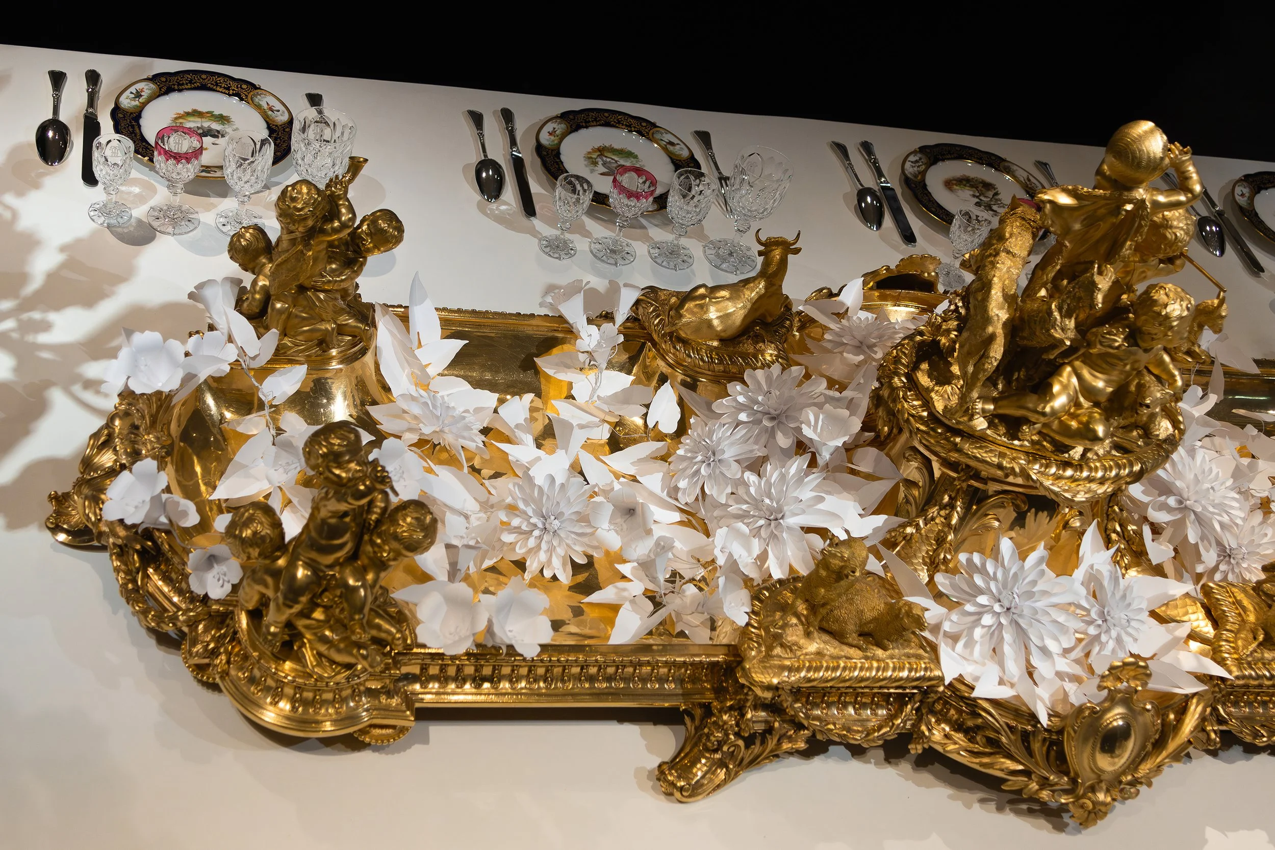 Grand ceremonial table installation featuring monumental gilded Christofle centerpieces and white paper floral compositions, Musée des Arts Décoratifs, Paris.